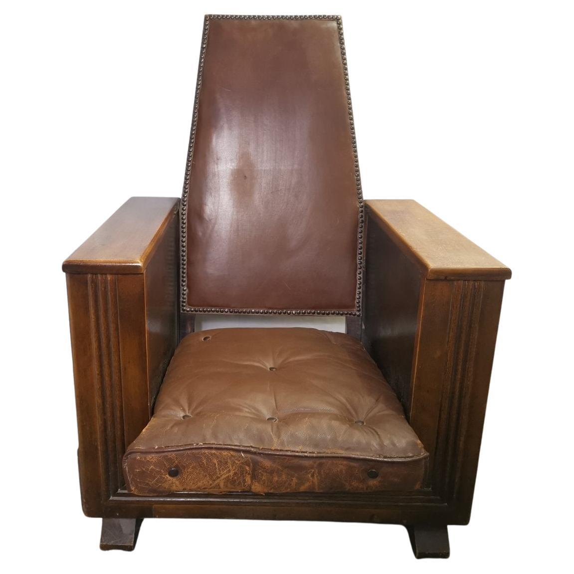 In the style of Heals of London.
A later Arts & Crafts fireside reading armchair with flat arms and a magazine rack to one side and bookshelves to the other side. Retaining the original leather cushion and the original leatherette back.
A tramline
