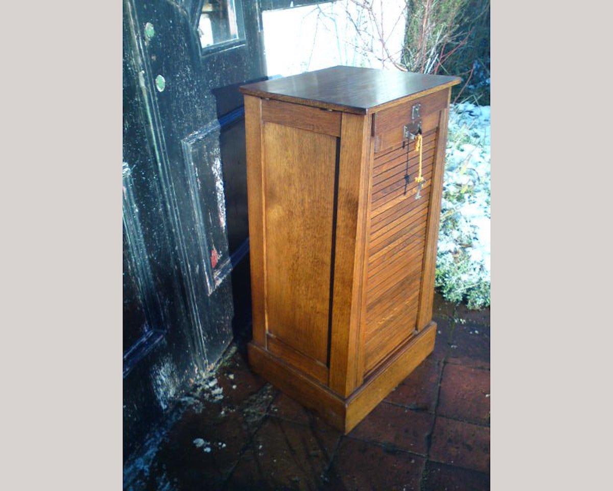 A rare Arts & Crafts oak record cabinet for holding 1978 (LP's do not fit into this cabinet but singles do). With a roll up door retaining the original key with a pair of upper and lower slide out compartmentalized drawers inside.
Measures: Height