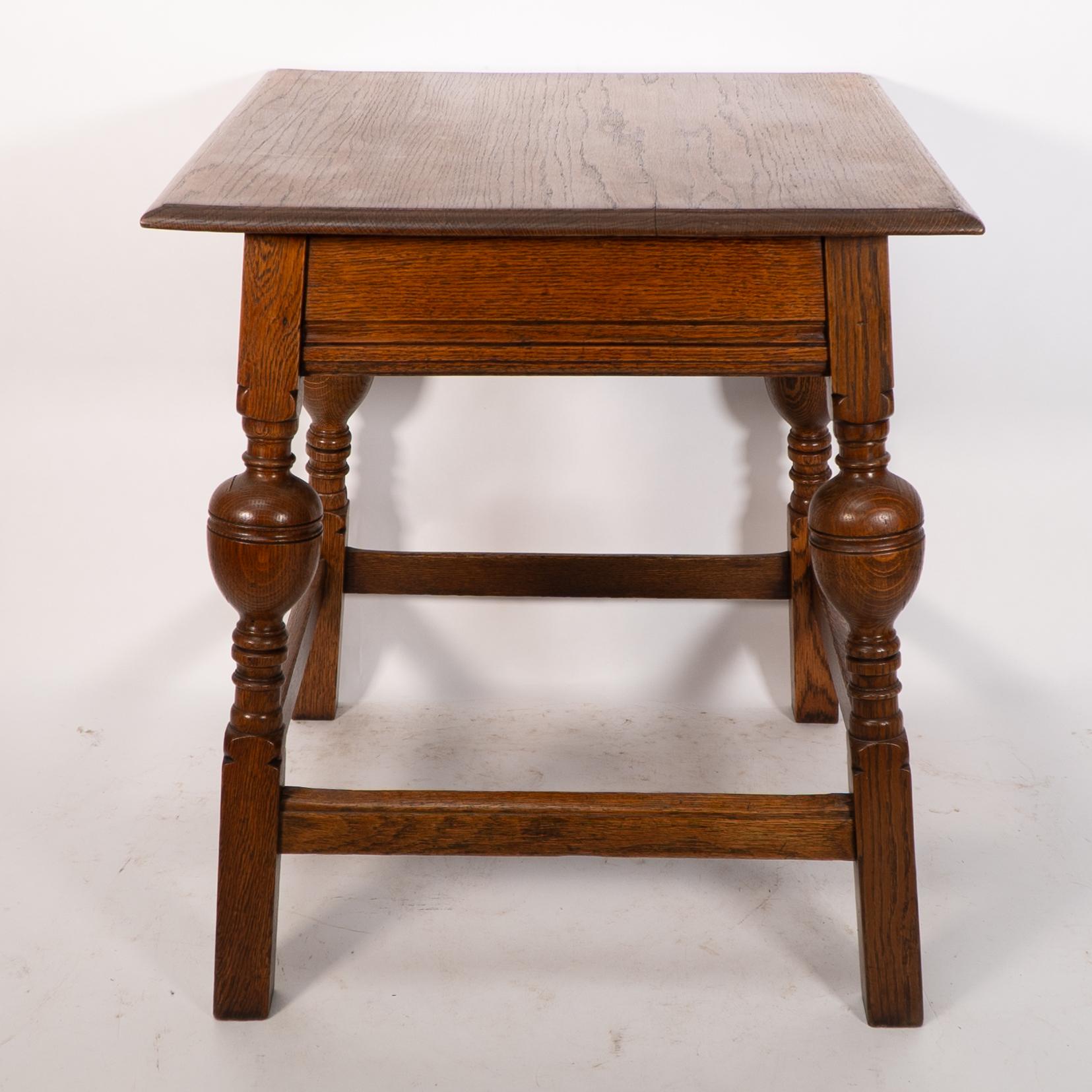 Liberty and Co. An oak Arts and Crafts side table with a moulded edge and line decoration to the lower apron below, the splayed legs with turned and bulbous details to the centres, united by a wrap around stretchers with moulded details to the top