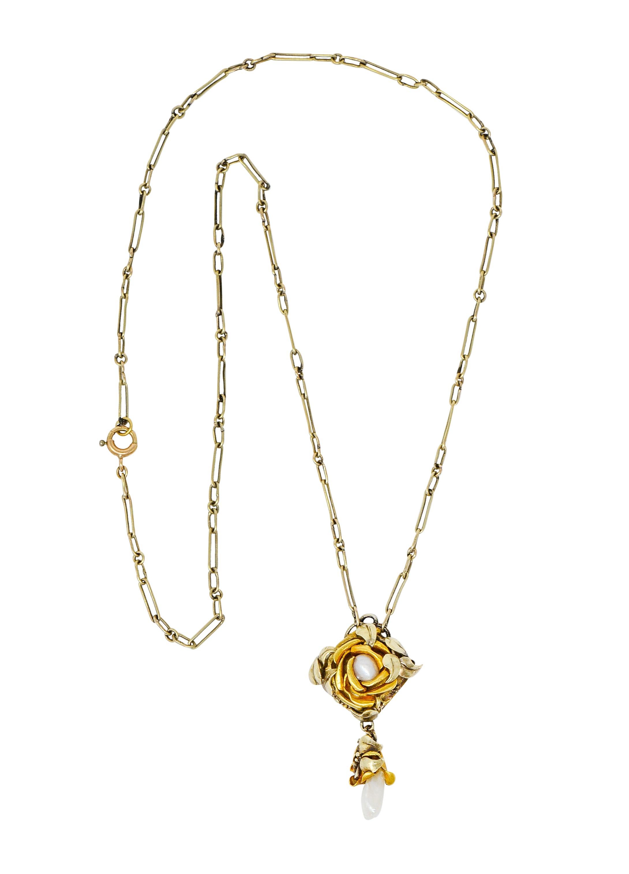 Paperclip style chain centers a fabricated rose comprised of yellow and green gold petals and leaves

Centering a semi-baroque oval pearl, white in color with slight rosè overtones and very good luster

Suspending a matching foliate drop accented by