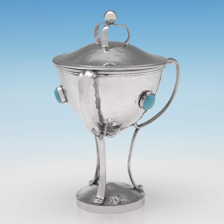 Hallmarked in London in 1909 by Charles Boyton, this very striking, antique sterling silver cup & cover, is in the Arts & Crafts taste, featuring a hammered finish, and inset with turquoise cabochons. The cup & cover measures 6.5