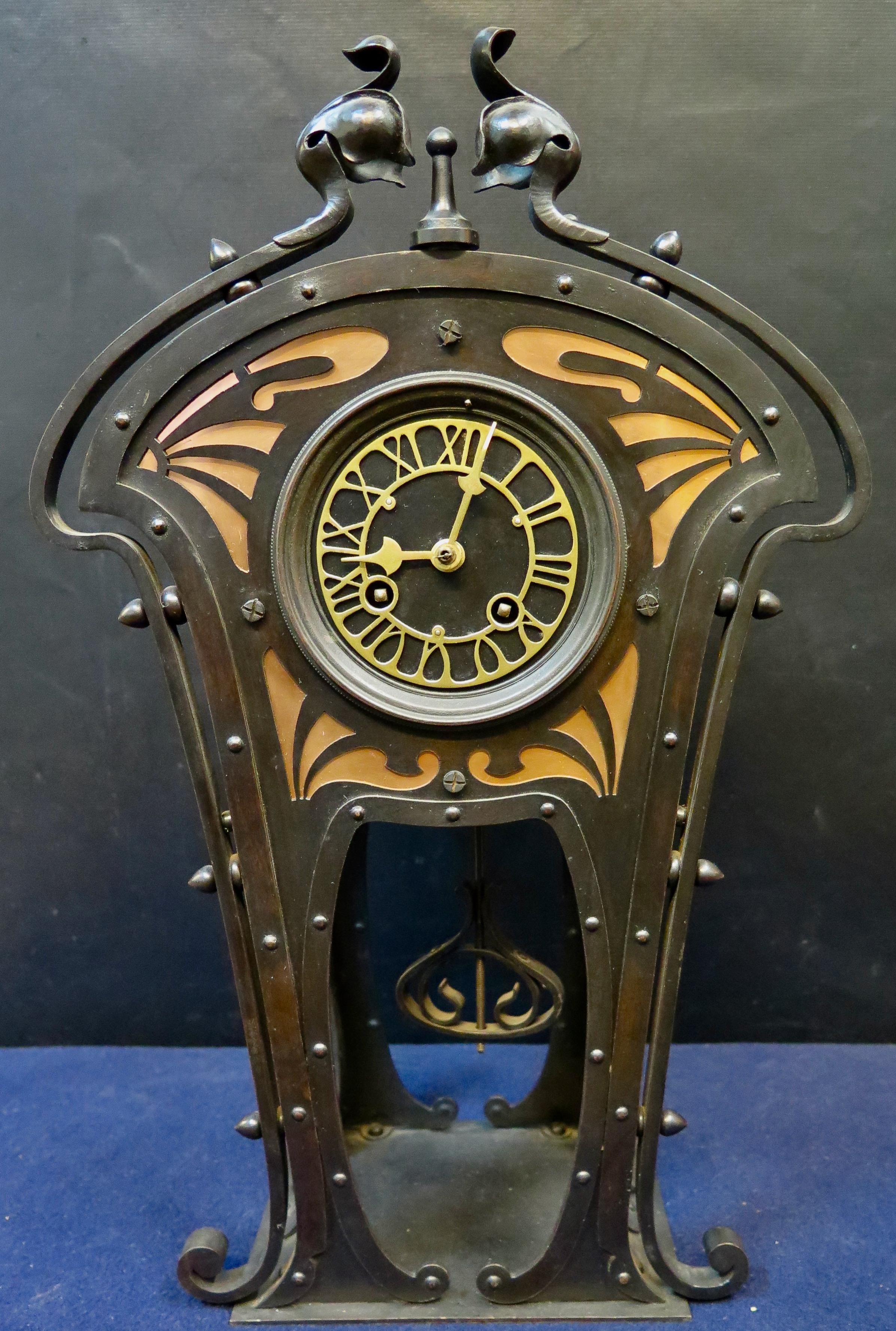 This vintage early 20th century “Arts & Crafts” three piece clock set is beautifully hand crafted with a blackened wrought iron exterior. The clock is designed with an exceptional flowing scrolled motif dominating the appearance. This motif is