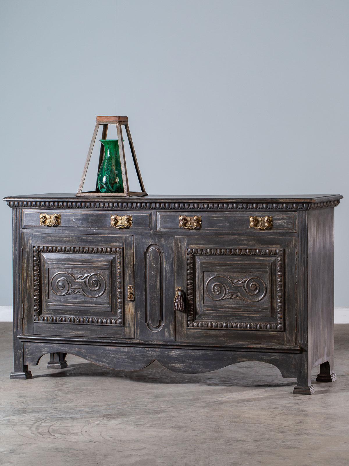 A super cool Arts & Crafts period antique English painted buffet circa 1900 with the original brass hardware. The bold and sculptural lines of this English buffet are emphasized by both the carved details and the complementary shape of the brass