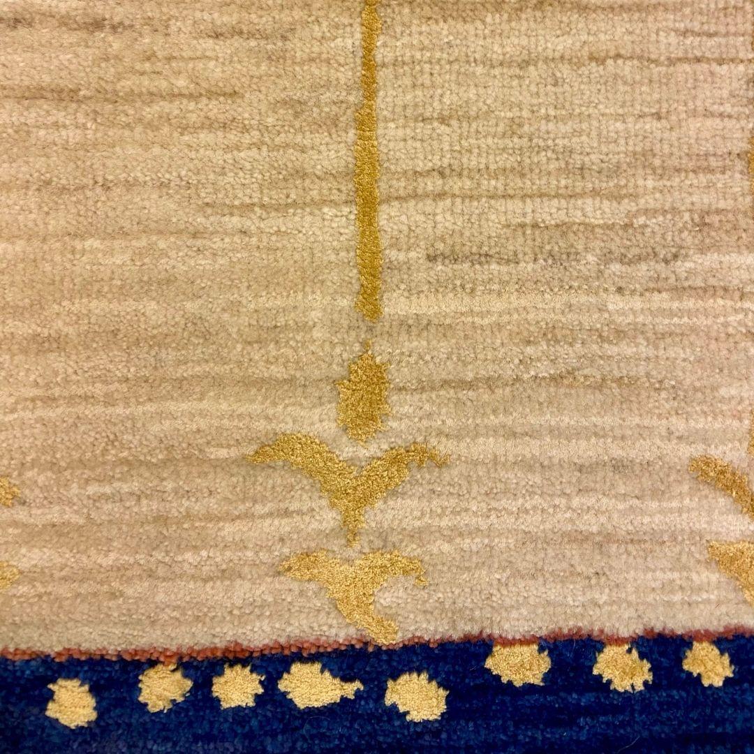 This Arts & Crafts cream, blue, green, and gold wool Persian rug, sized at 2' x 3', is a testament to timeless design and exceptional craftsmanship. The rug’s soft cream field provides a serene and neutral foundation, while a refined green band