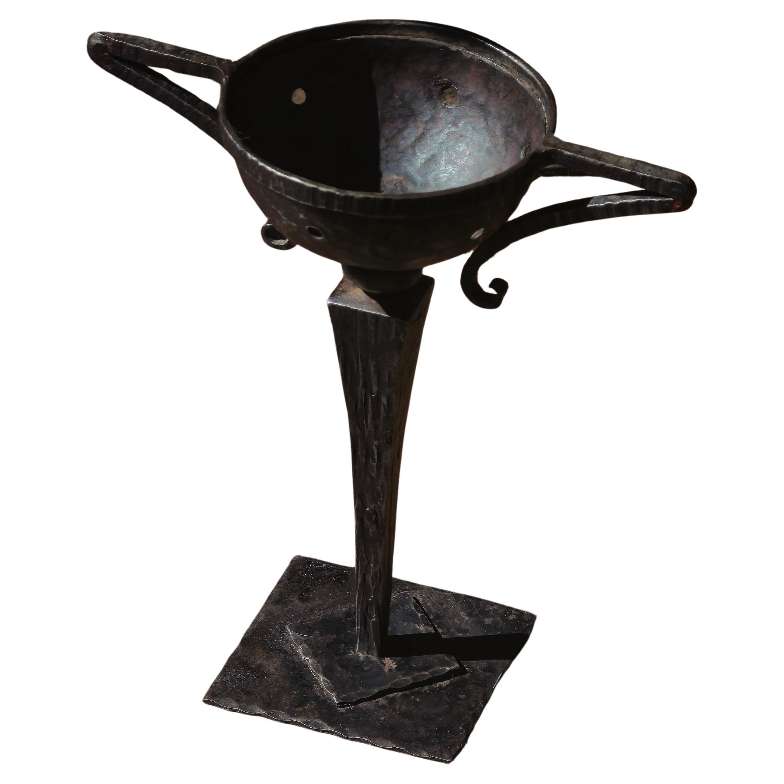 A small Arts & Crafts tazza in hand-hammered metal, featuring a pierced bowl with two detached handles. The flared stem rises from a boldly shaped quadrangular base, showcasing the movement’s signature craftsmanship and sculptural geometry. A rare