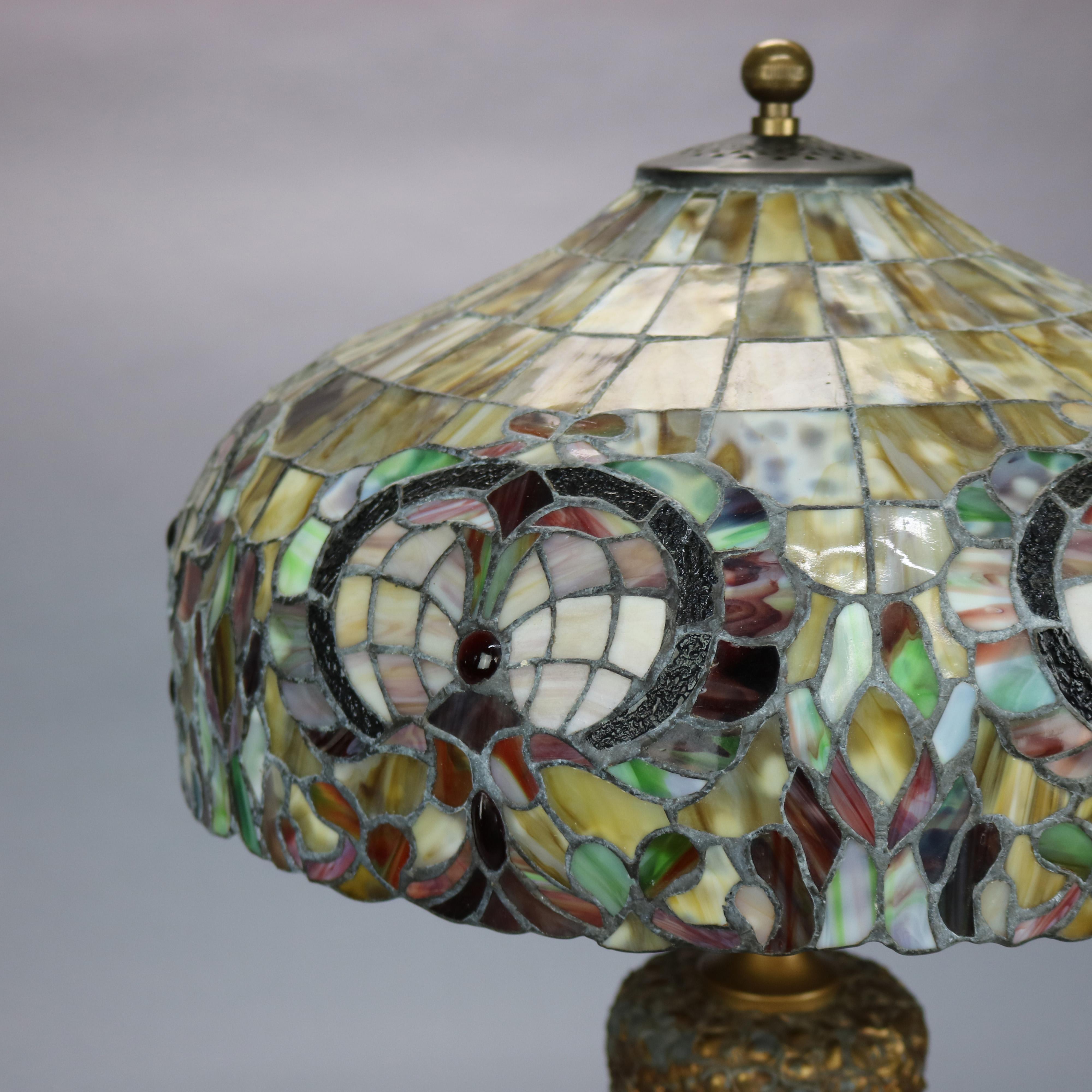 An antique Arts and Crafts lamp by Pittsburgh Lamp Co. offers floral and foliate cast urn form double socket base with contemporary mosaic leaded glass shade, base is unsigned as is customary and guaranteed Pittsburgh Lamp Co., c1910

Measures: