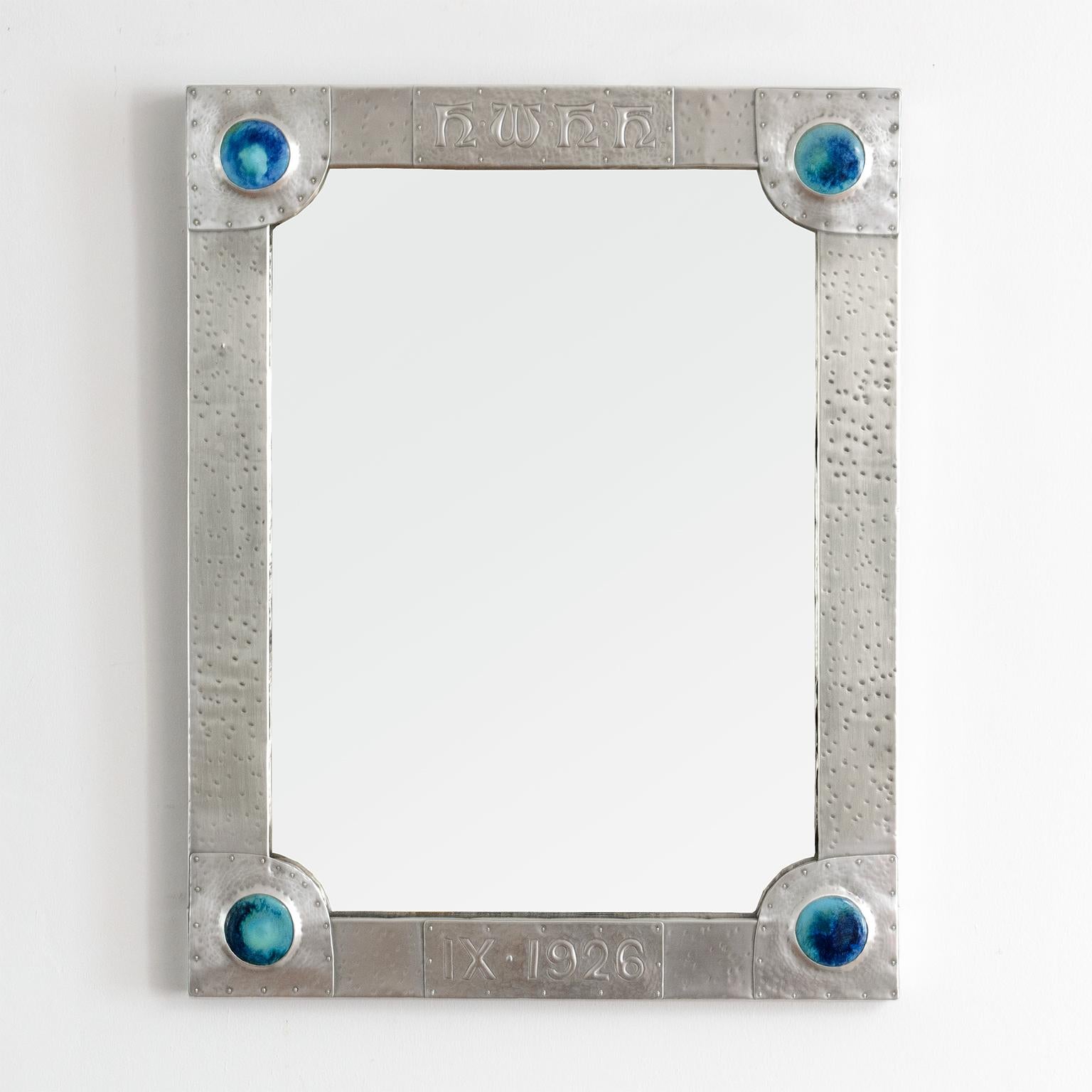 An Arts & Crafts era polished pewter mirror detailed with enameled 