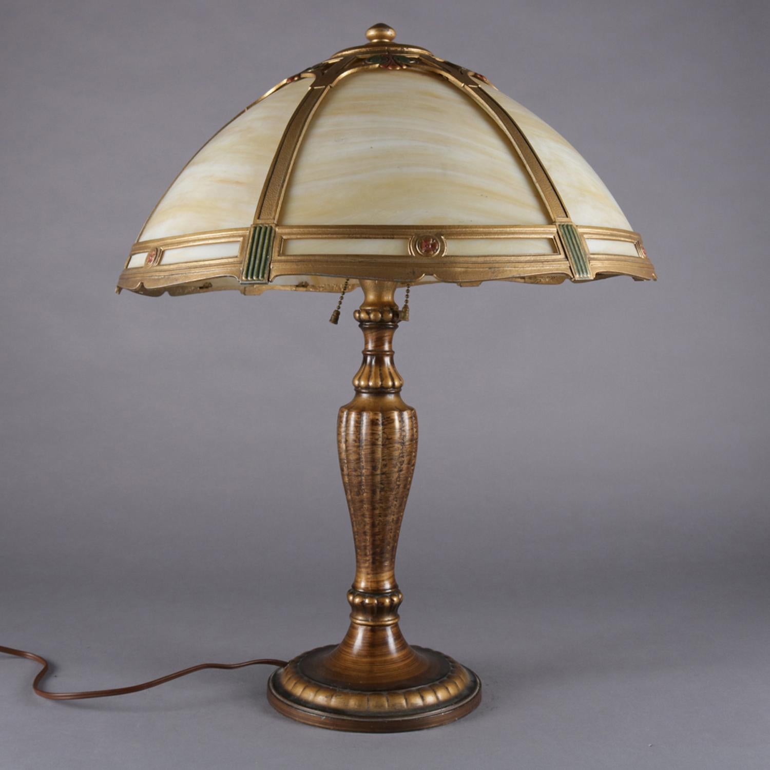 Arts & Crafts table lamp by Jefferson features cast and bronzed metal base with two independently controlled pull chain light sockets, shade with polychromed frame having stylized floral and scroll decoration and housing six bent slag glass panels,