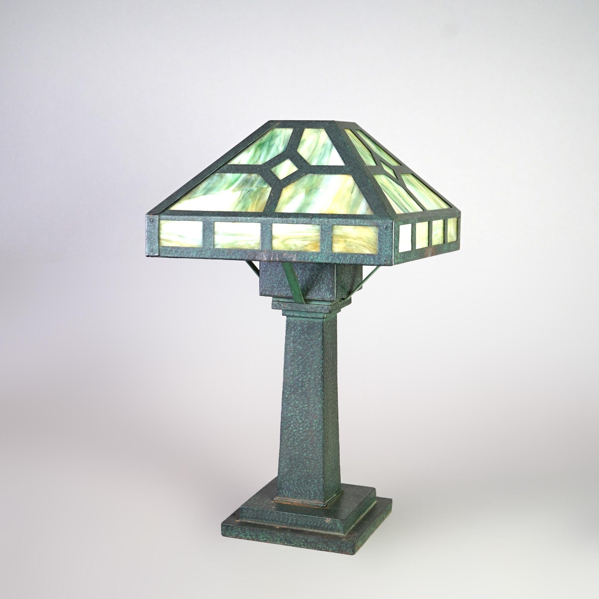 An Arts and Crafts Mission Prairie style table lamp offers verdigris single socket base with shade having slag glass panels, c1910

Measures - 20.5