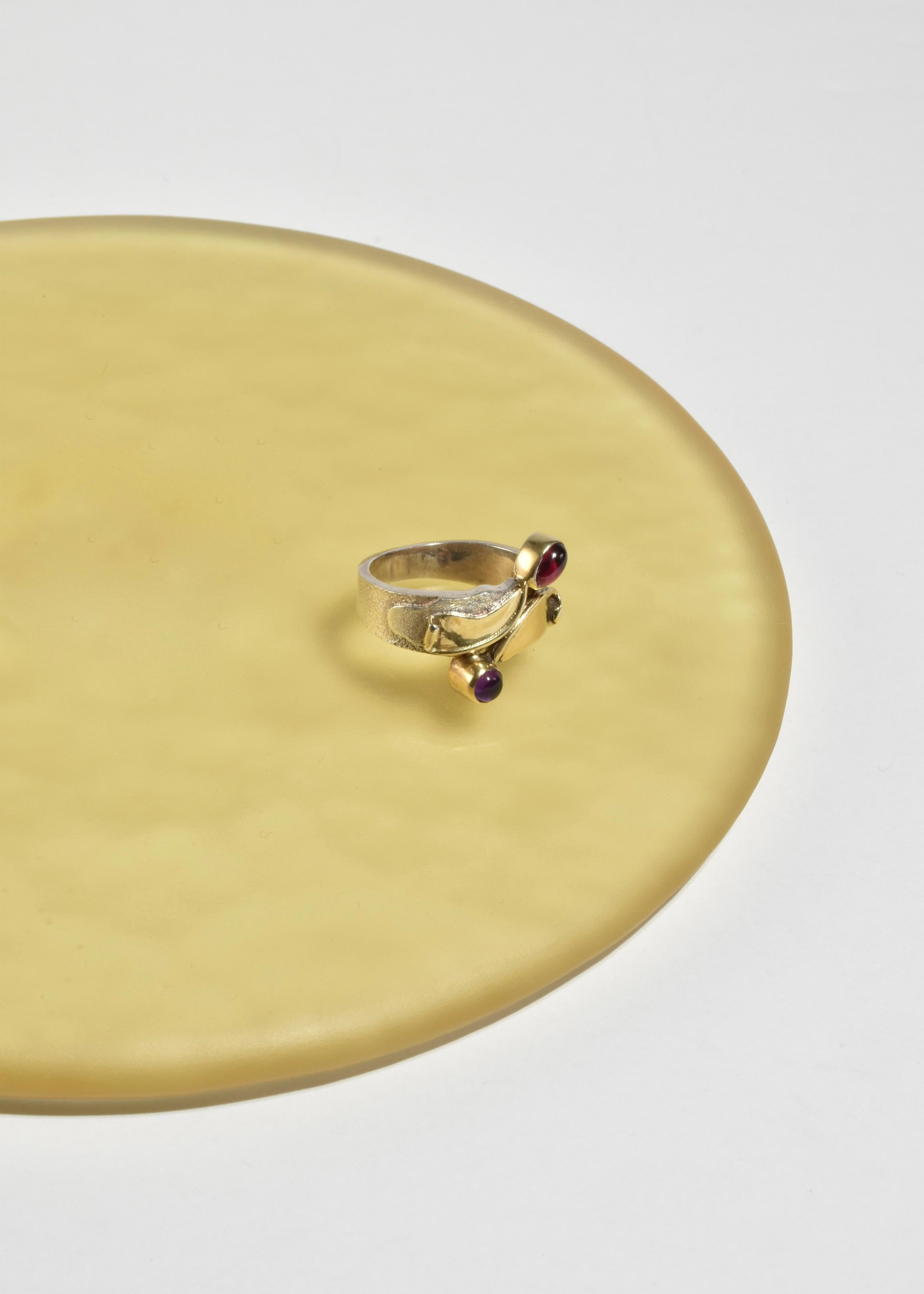 Raro anello vintage fatto a mano in sterling in stile arts and crafts con dettagli in oro e pietre di granato e ametista. Timbro 925.

Materiale: Argento, oro 14k, ametista, granato.