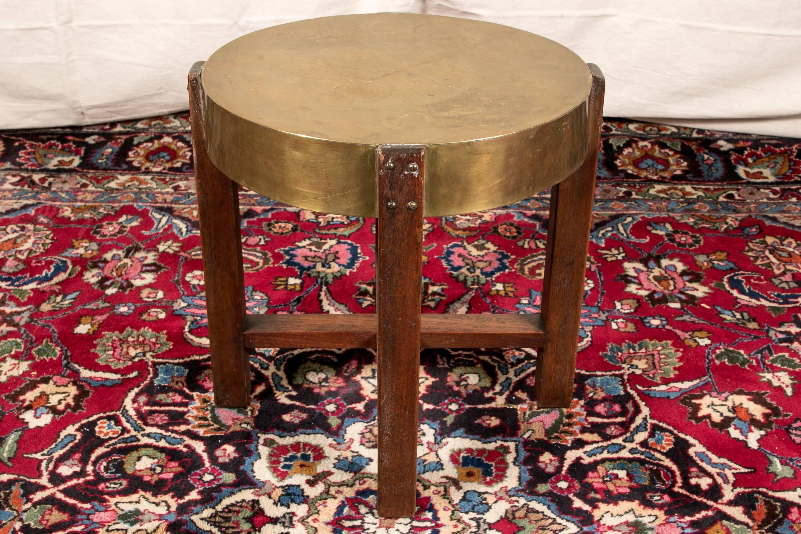 Arts & Crafts side table, circular brass top supported by mahogany base, two cross-stretcher bases.

Condition: Expected wear and signs of use including some surface scratching and sporadic nicking, some discoloration and oxidation top.