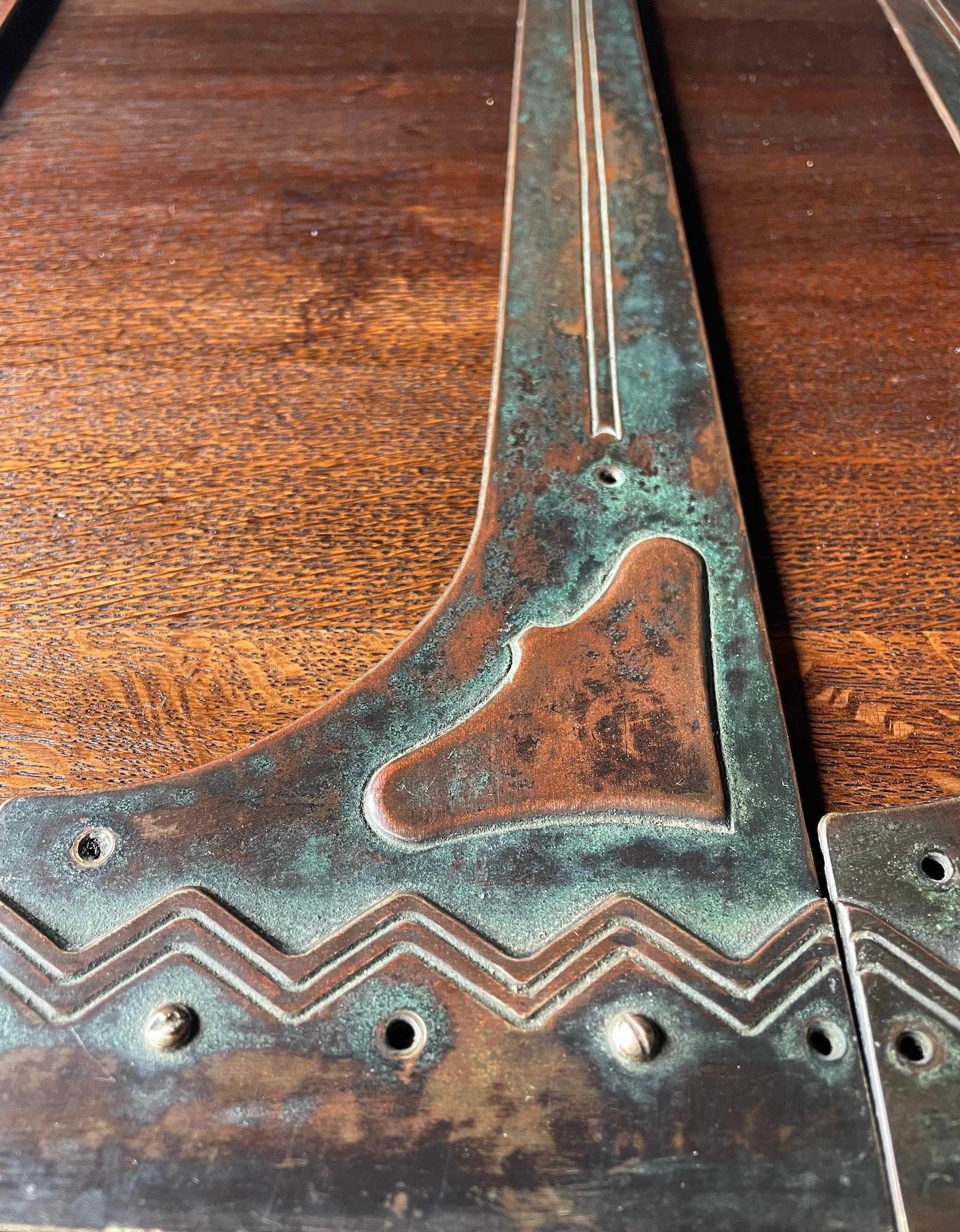 A set of 4 Arts and Crafts strap hinges with stylised flower head and raised heart detail. Patinated brass. 

Length 46cm

Width 10cm flower head 8.5cm