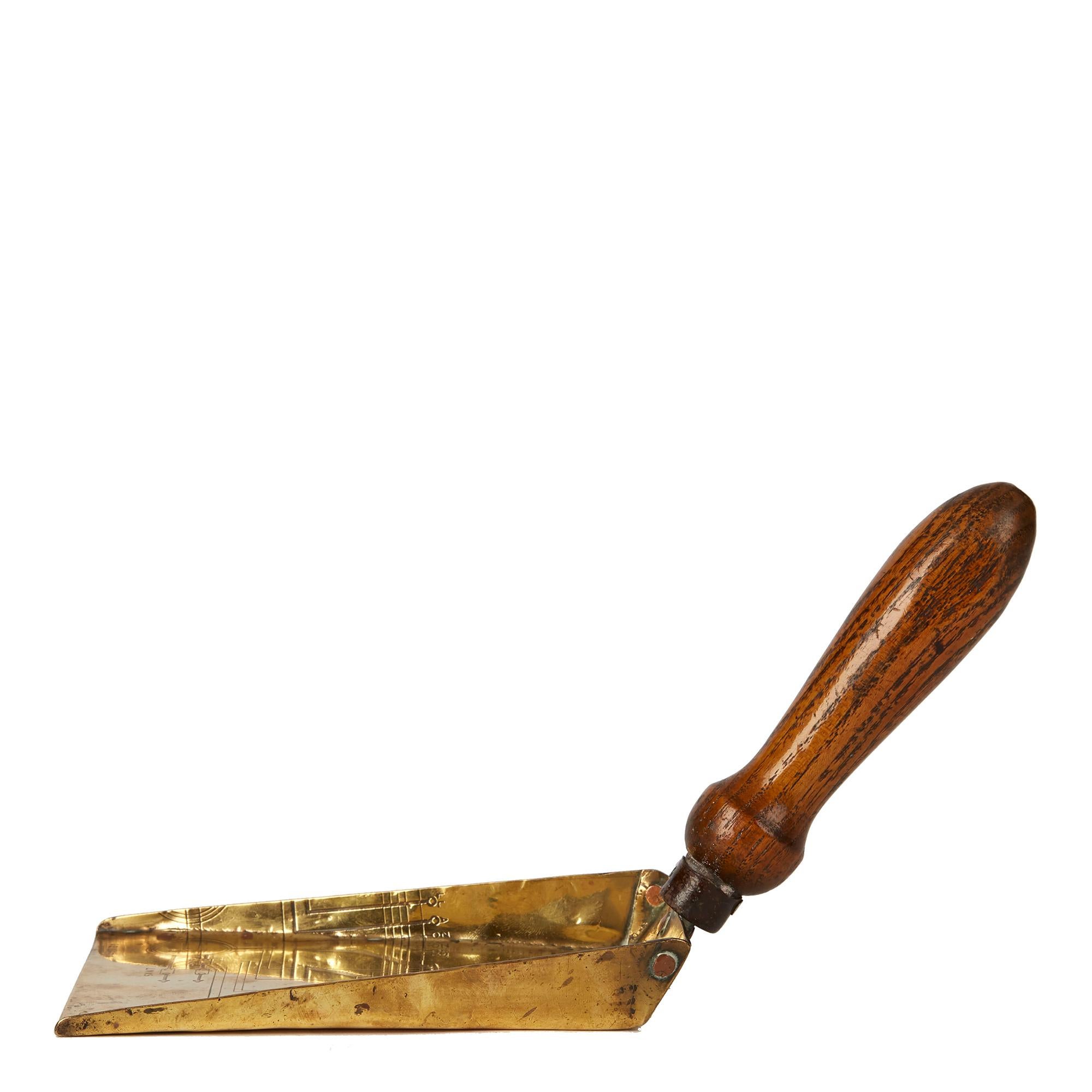 A very unusual and rare Arts & Crafts hand shovel of flat wide shape with a shaped oak handle, the main body in brass and attached with copper rivets. The body of the shovel has a diagram titled 'M' POTENTIOMETER, the diagram is finely engraved into