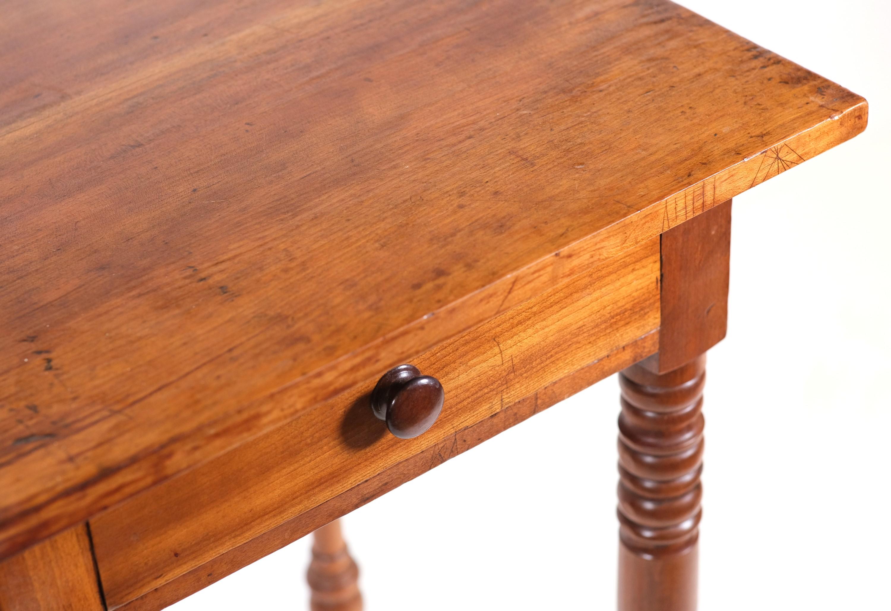 Arts & Crafts style side table with turned legs and one dovetailed drawer. This side table has a dark tone wood made of pine and maple. There is one wood knob for the drawer. This can be seen at our 2420 Broadway location on the upper west side in