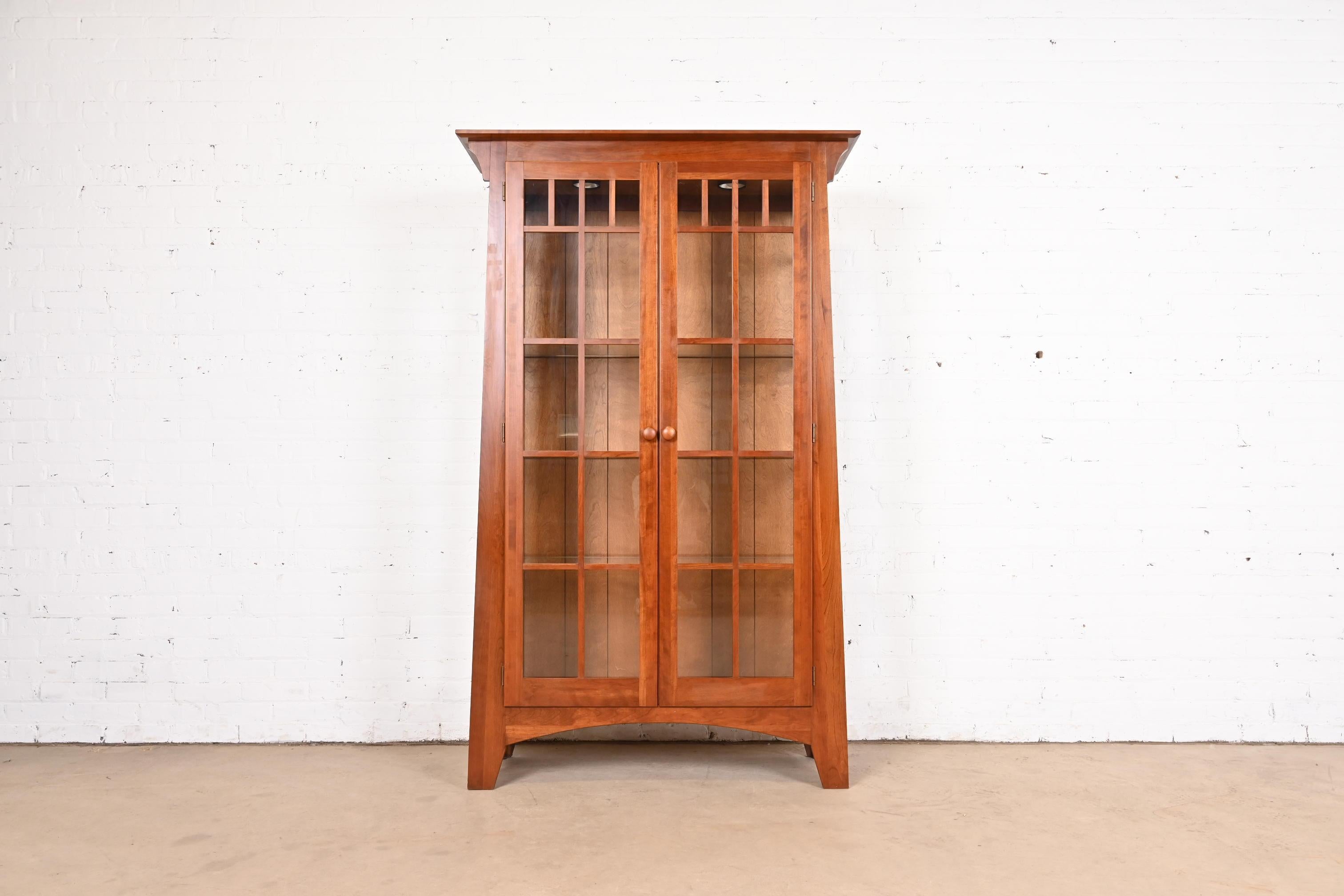 A gorgeous Mission or Arts & Crafts style lighted display cabinet or bookcase

In the manner of Gustav Stickley or Harvey Ellis

USA, Circa 1990s

Solid cherry wood, with mullioned glass front and sides.

Measures: 43