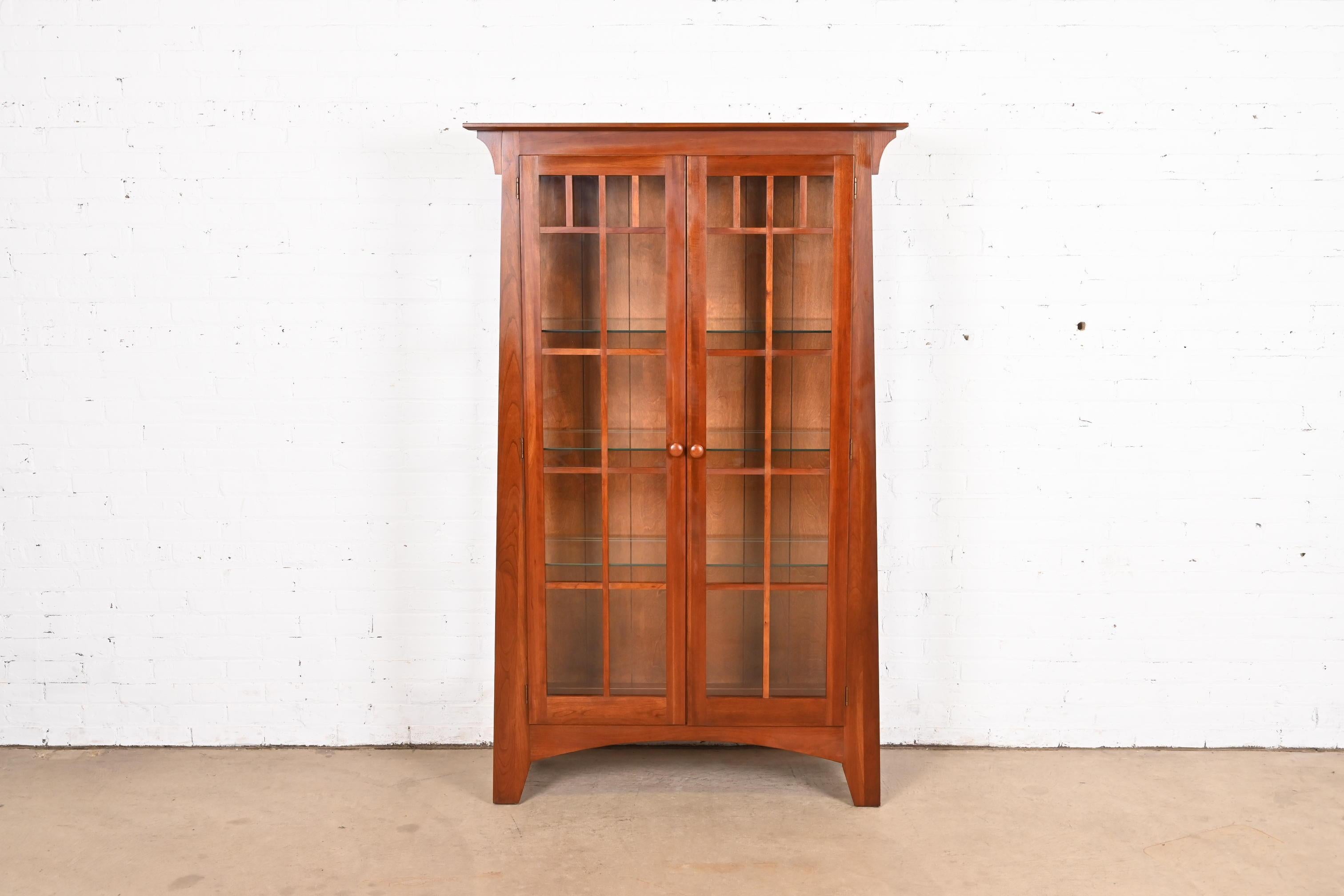 A gorgeous Mission or Arts & Crafts style lighted display cabinet or bookcase

In the manner of Gustav Stickley or Harvey Ellis

USA, Circa 1990s

Solid cherry wood, with mullioned glass front and sides.

Measures: 43