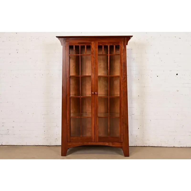 A gorgeous Mission or Arts & Crafts style lighted display cabinet or bookcase

In the manner of Gustav Stickley or Harvey Ellis

USA, Late 20th Century

Solid cherry wood, with mullioned glass front and sides.

Measures: 43