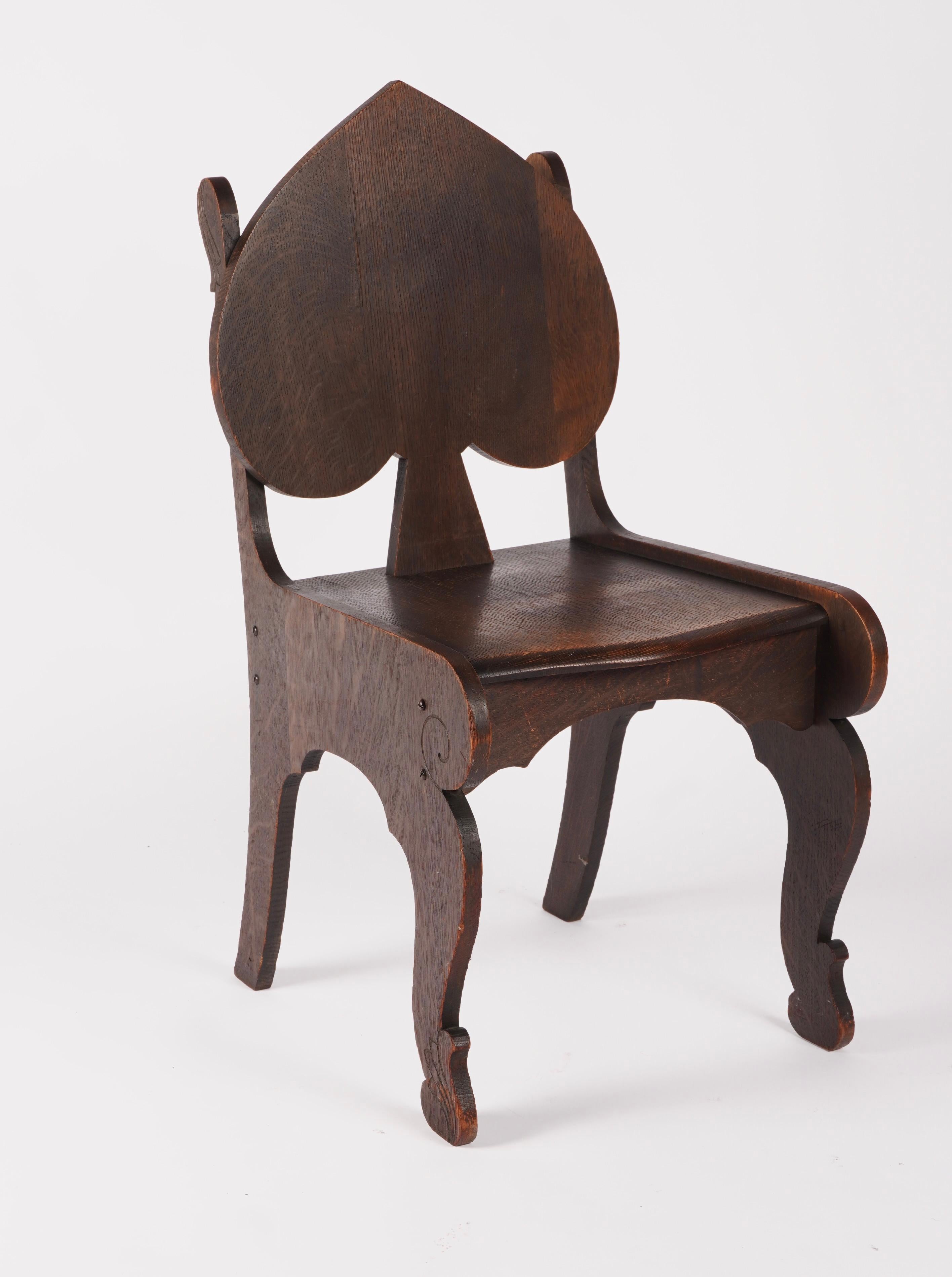 Fumed oak finish spade back side chair, nice carving accent details on various areas of the chair. The finish is a very dark brown - black fumed oak with lighter areas from use and age. An unique shape and fun design from the early 20th century. 