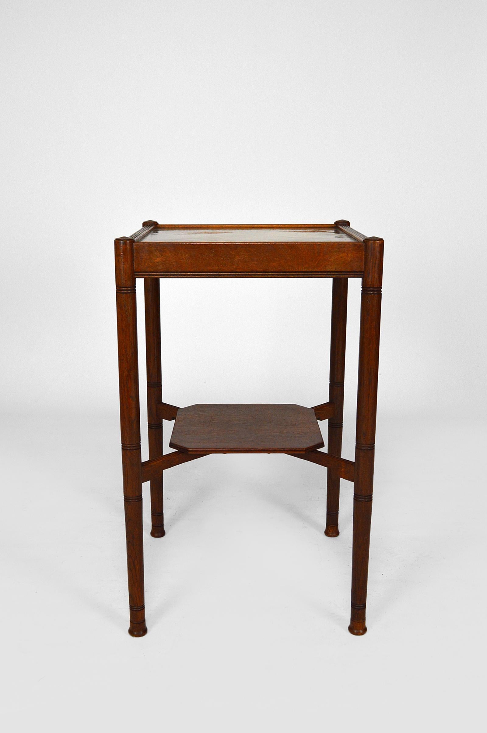 Elegant side table / pedestal table in Arts & Craft style.
Carved oak structure. Square hammered brass tray.

United Kingdom, mid-late 19th century.
Style Arts & Crafts / Aesthetic Movement.
In the manner of Edward William Godwin (1833-1886),