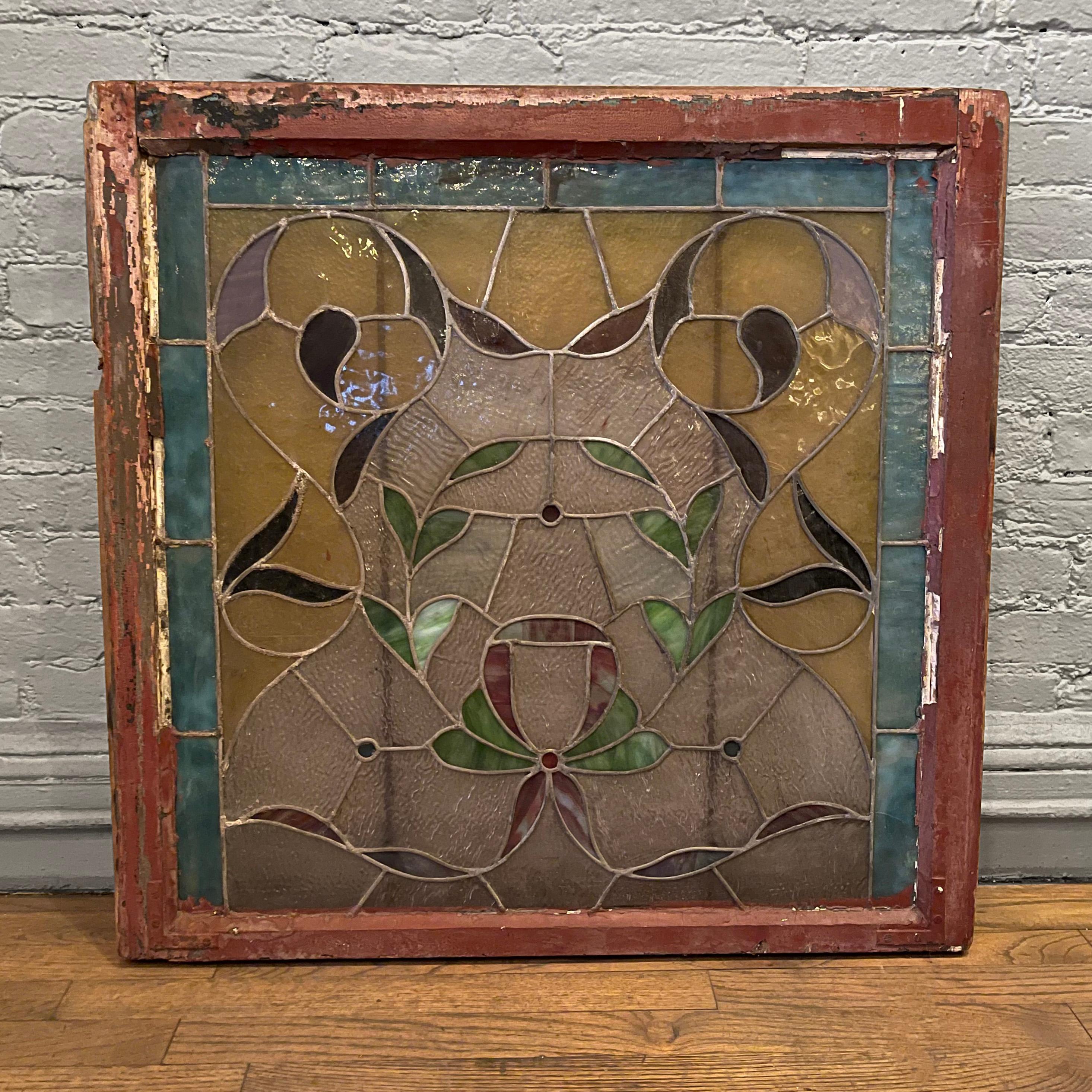 Arts & Crafts, lead-lined, stained glass window panel features a foliate wreath design with rustic painted wood frame.