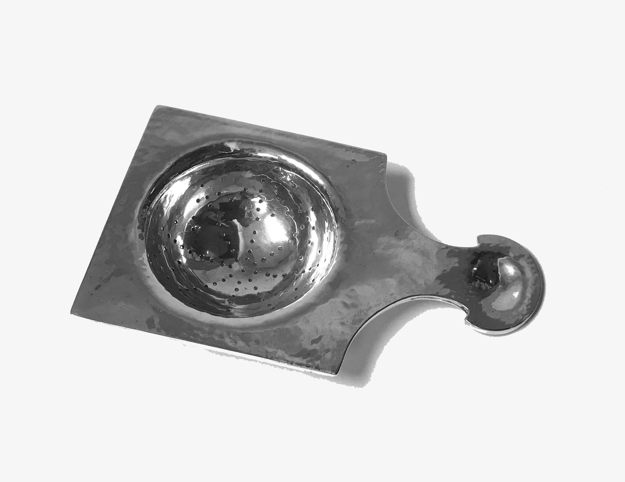 Arts & Crafts silver tea strainer, Emmy Roth, Germany, circa 1920. The hammered silver strainer of plain square form with curvilinear stylised handle. Full marks to reverse. Measures: 4.75 x 3.00 x 1.00 inches. Weight: 66.50 grams. Emmy Roth