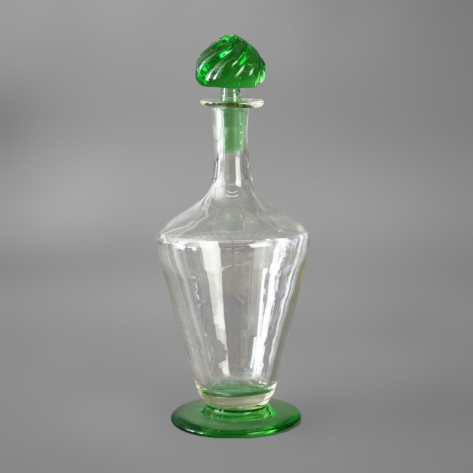 Ein antiker Dekanter, der Steuben zugeschrieben wird, bietet eine Konstruktion aus grünem und farblosem Kunstglas in konischer Form und mit gewirbeltem Stopfen, um 1920

Maße - 13 