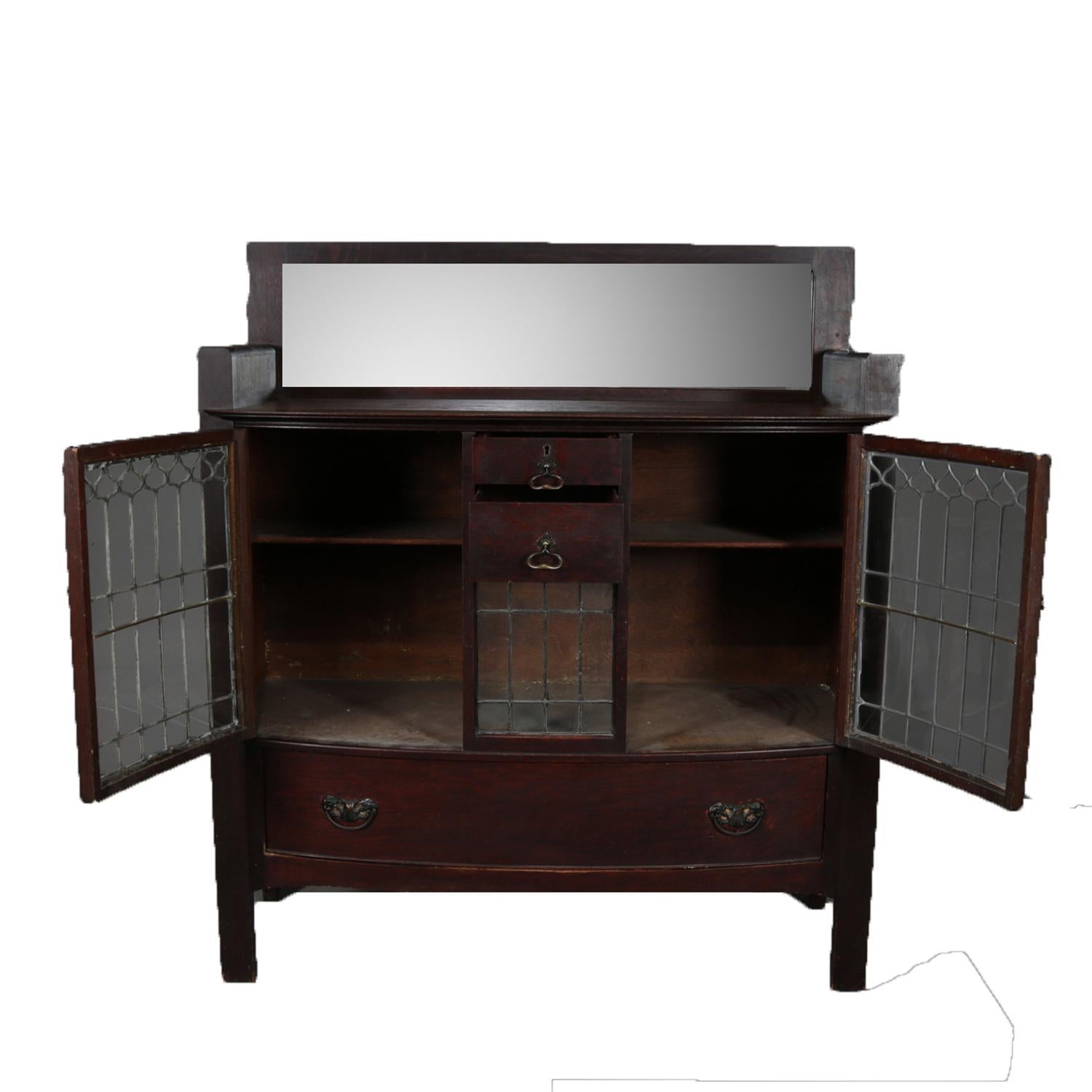 Antique Arts & Crafts Stickley Brothers & Co. server features oak construction with mirrored backsplash over case with central drawers flanked by leaded glass doors and over single long drawer, en verso original tag, circa 1910.

Measures: 55.25