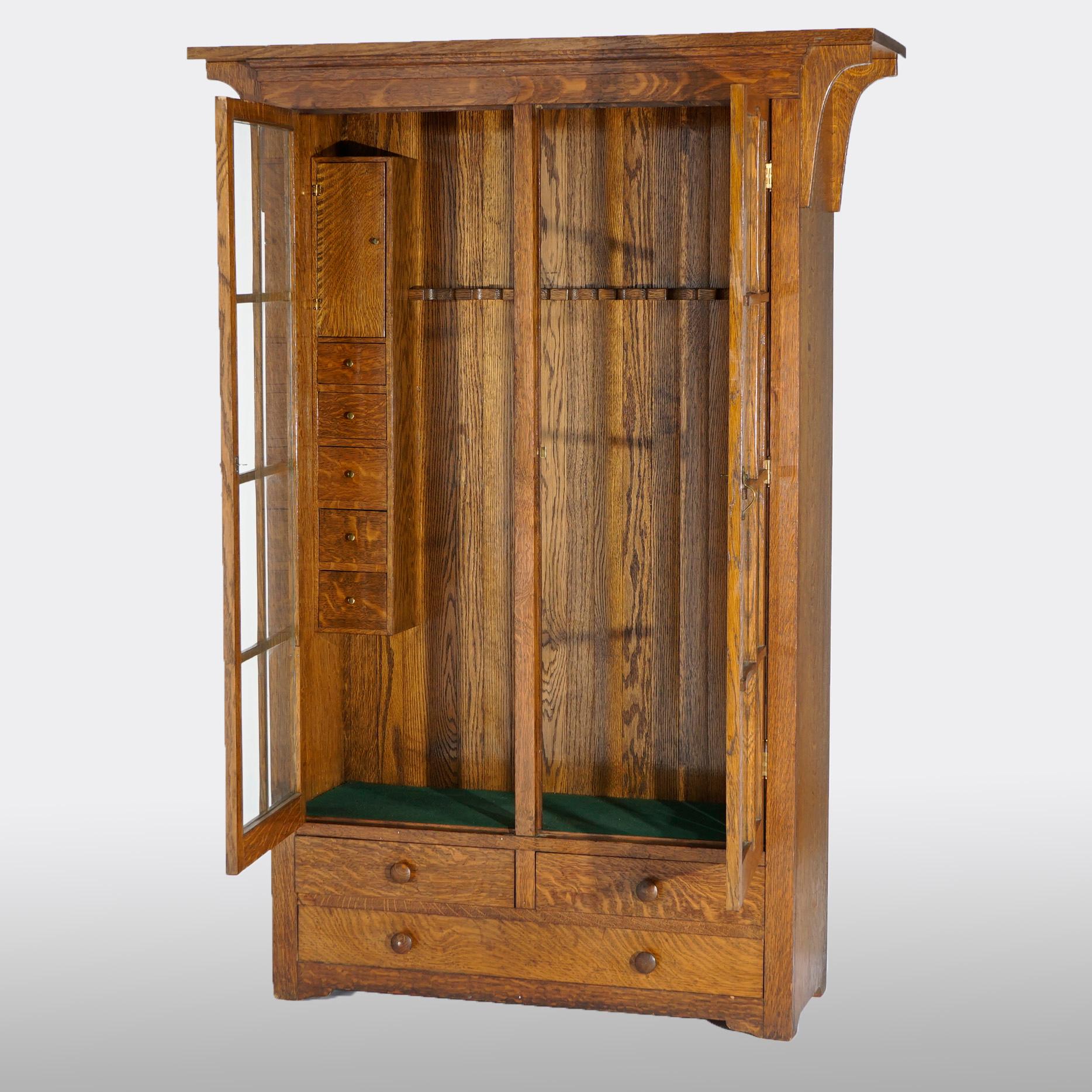 An antique arts & Crafts custom-made gun cabinet in the manner of Stickley offers quarter sawn oak construction with double glass doors opening to display interior with drawers, over base with two smaller drawers over single long drawer, craftsman