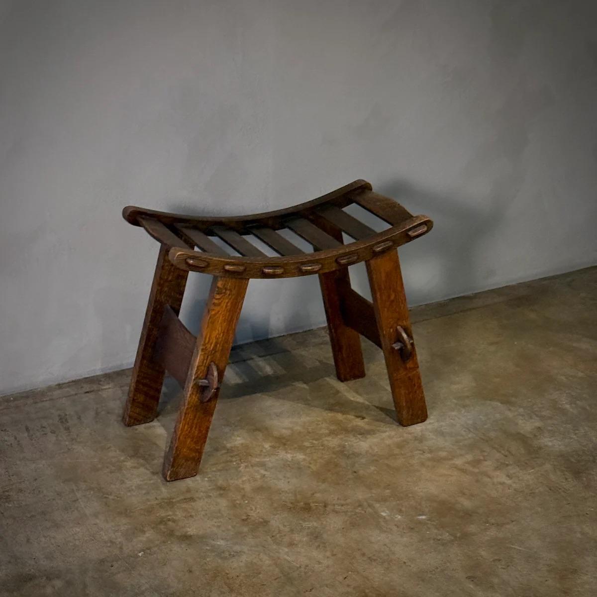 Dieser aus den Niederlanden stammende Hocker aus der Mitte des 20. Jahrhunderts im Arts & Crafts-Stil zeichnet sich durch sein stabiles, robustes Design mit einer tiefen, satten Lackierung aus, die seine massive Holzstruktur betont. Die
