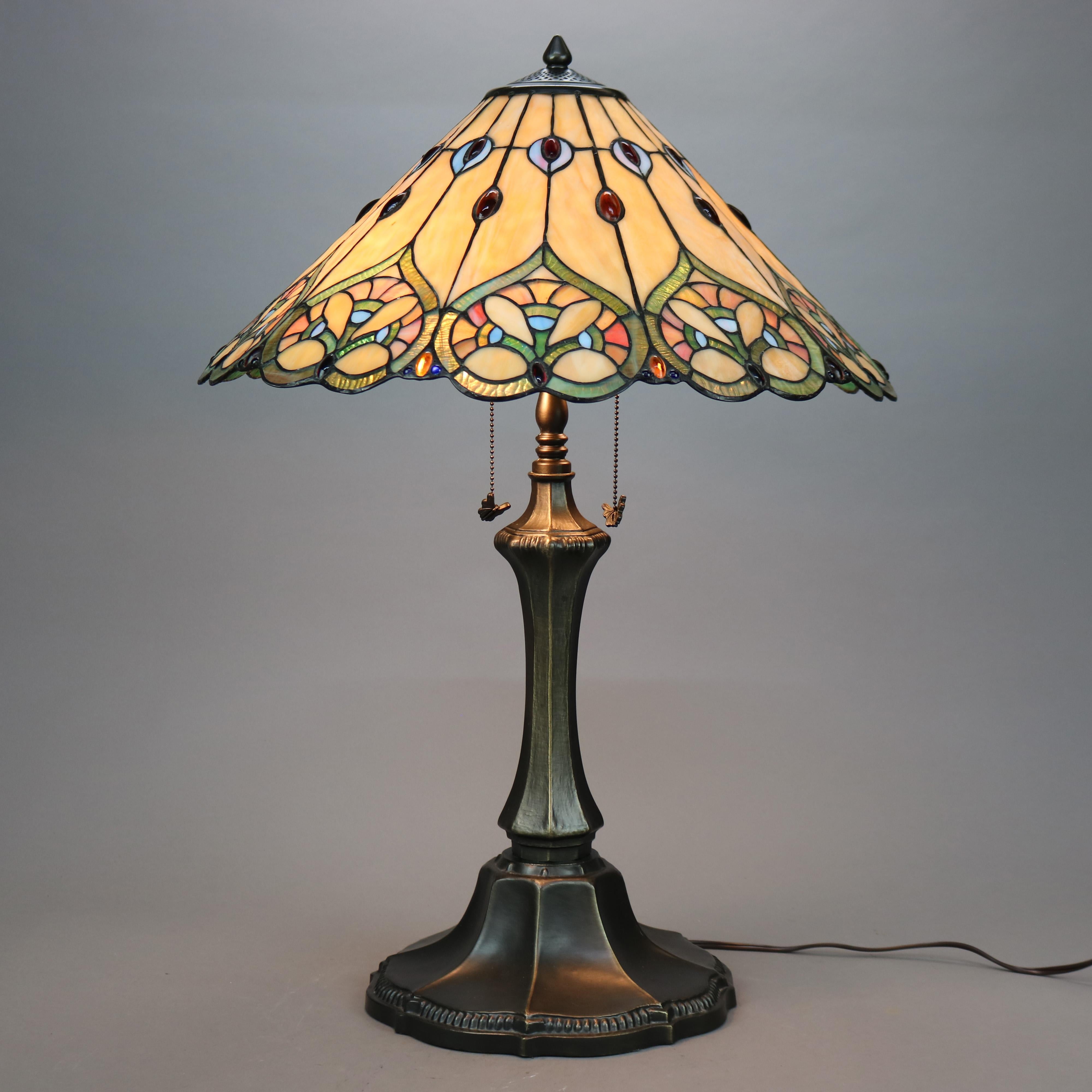 A Tiffany style table lamp offers a leaded stained glass conical shade having stylized floral design over double socket bronzed metal base, 20th century

Measures - 29.25''H x 21''W x 21''D.

Catalogue Note: Ask about DISCOUNTED DELIVERY RATES