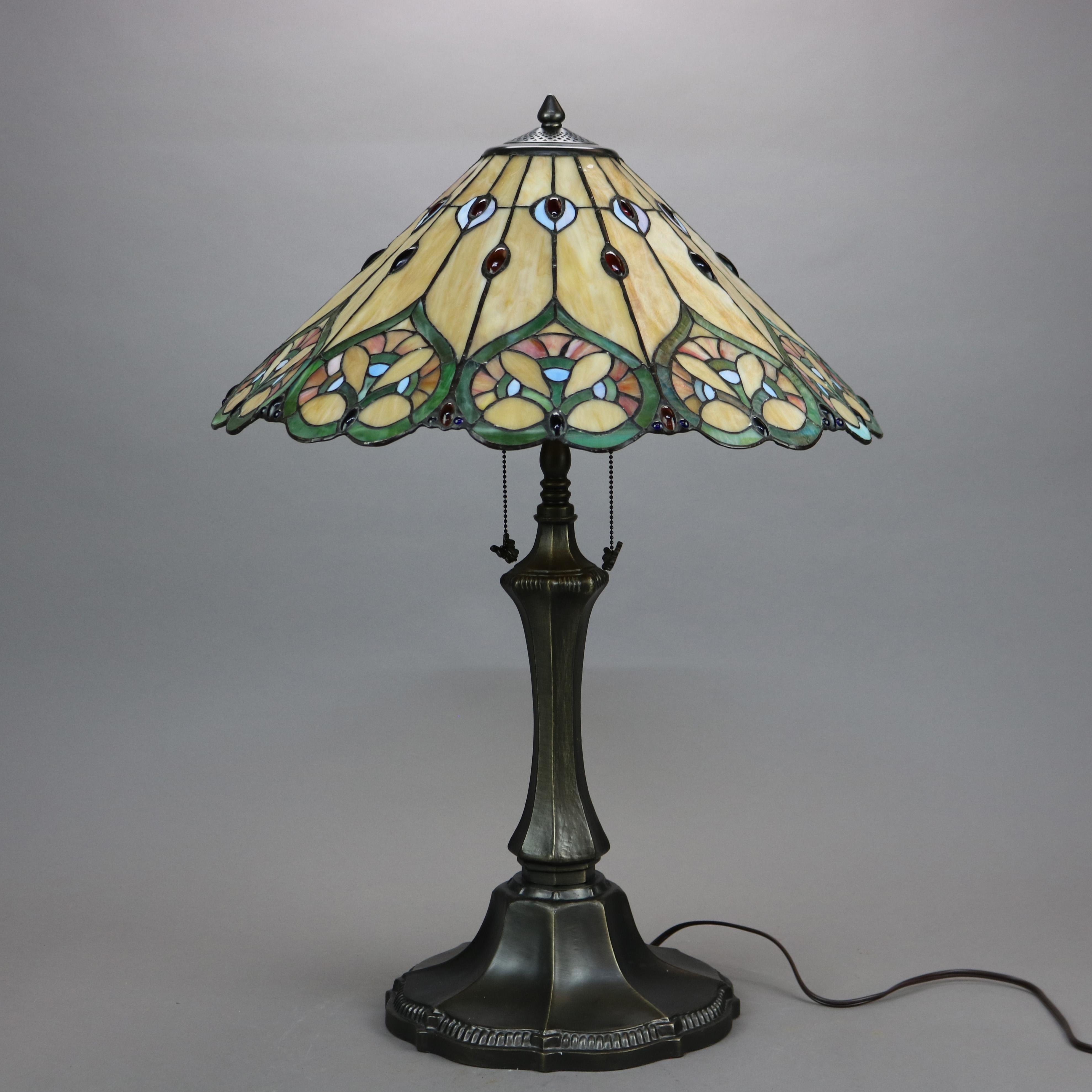 An Arts & Crafts Tiffany style table lamp offers a leaded stained glass conical shade having stylized floral design over double socket bronzed metal base, 20th century.

Measures- 29.75''H x 11''W x 11''D.