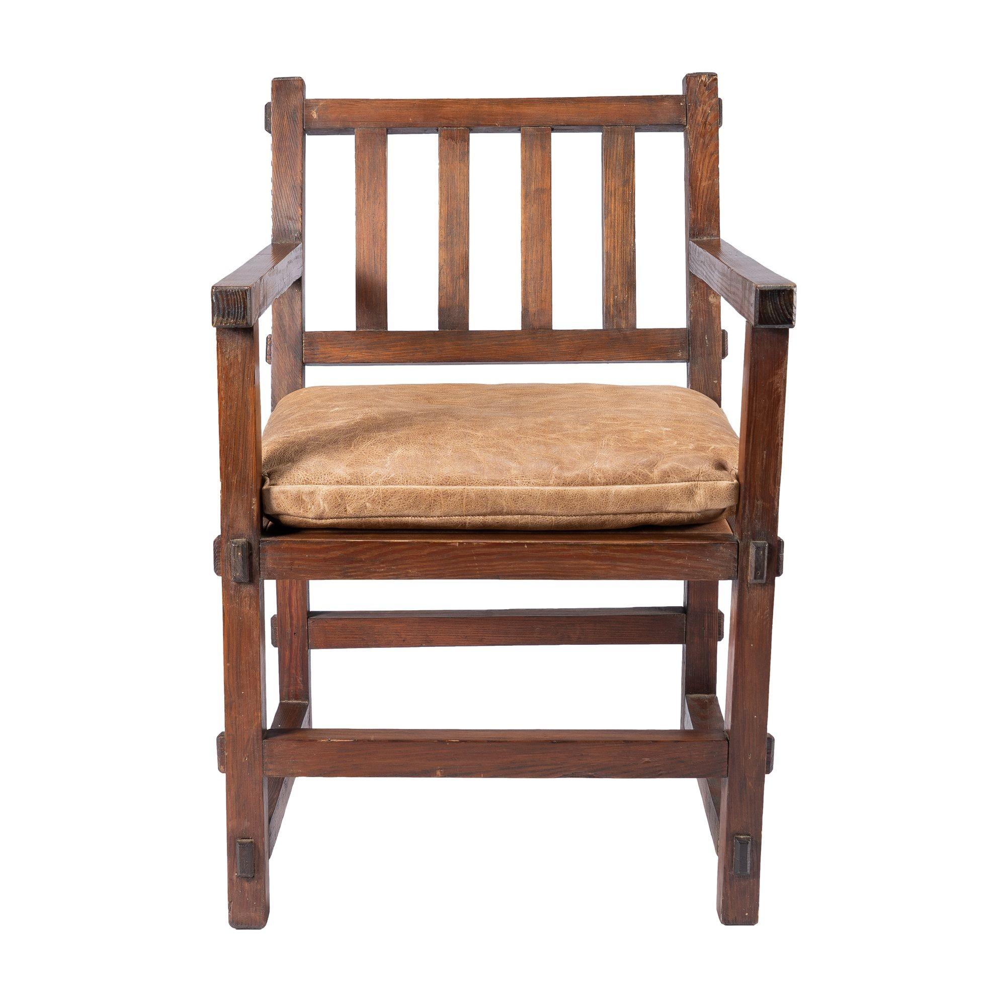 American Arts & Crafts armchair of stained hard yellow pine with leather upholstered seat. The frame is constructed entirely of 2” x 2” elements with mortice and thru tenons. Note the exposed and beveled tenon ends used as a decorative element in