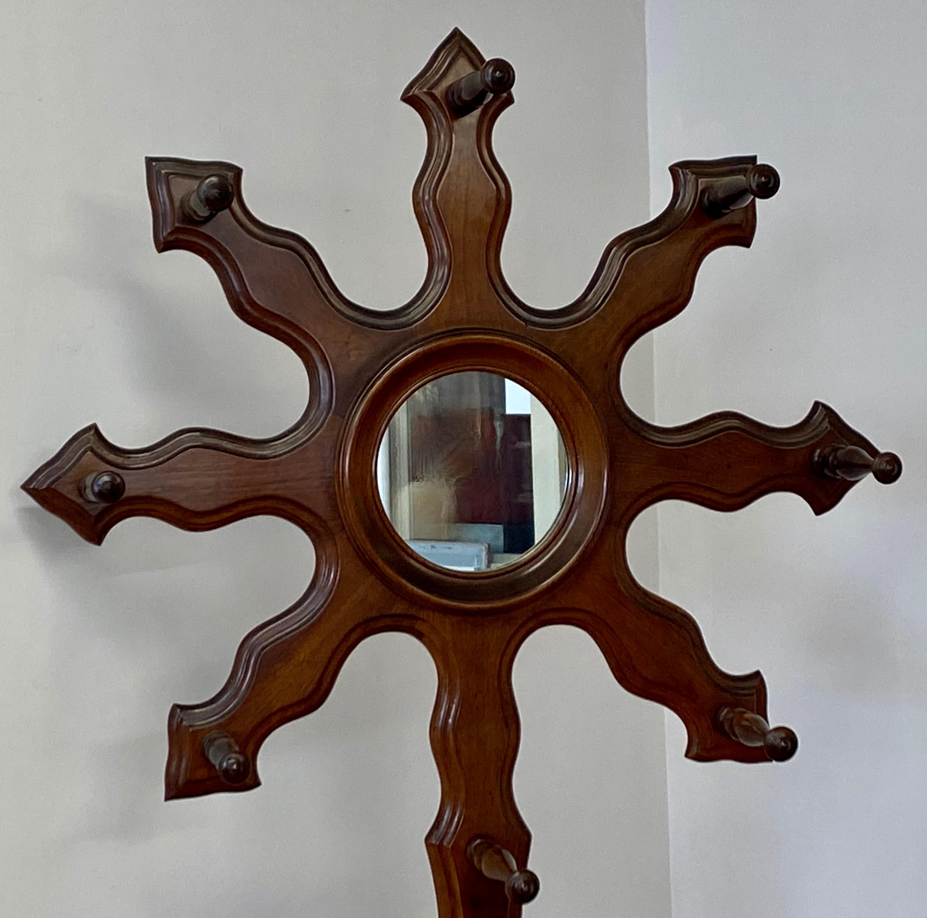 Arts & Crafts walnut sunburst hall tree

Free standing hall tree with eight coat hooks and umbrella stand

The center of the sunburst is a mirror 

Measures: 24