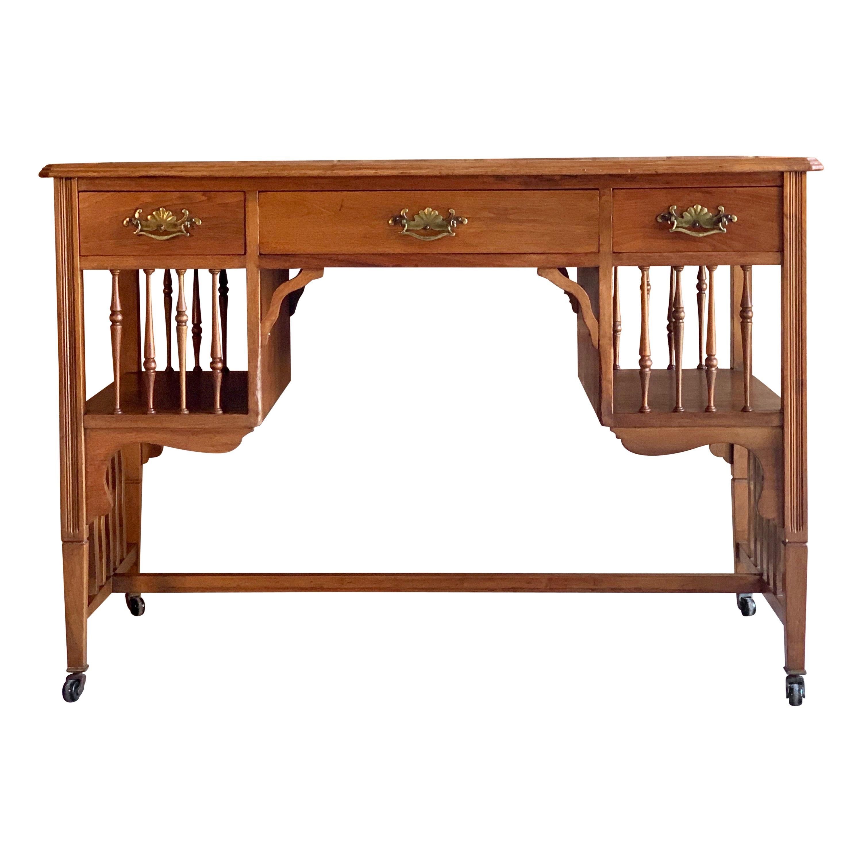 Magnificent Arts & Crafts walnut knee hole desk, circa 1920, in the style of J S Henry, the rectangular burgundy leather inset top with three frieze drawers each with brass drop handles flanked by two book shelves with spindled galleries to the