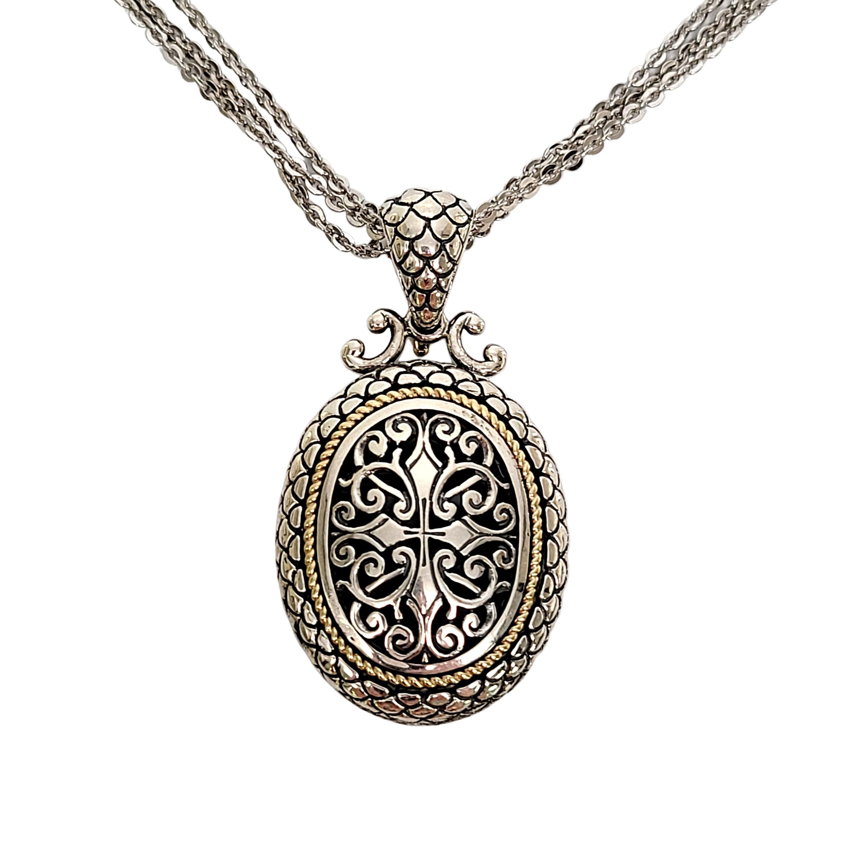 Arts Elegance sterling silver with gold accent oval pendant with multi-strand chain.

Beautifully ornate pendant featuring a yellow gold twist accent, open work design and textured frame. Hinges bale with safety lock. 3 strand chain.

Chain measures