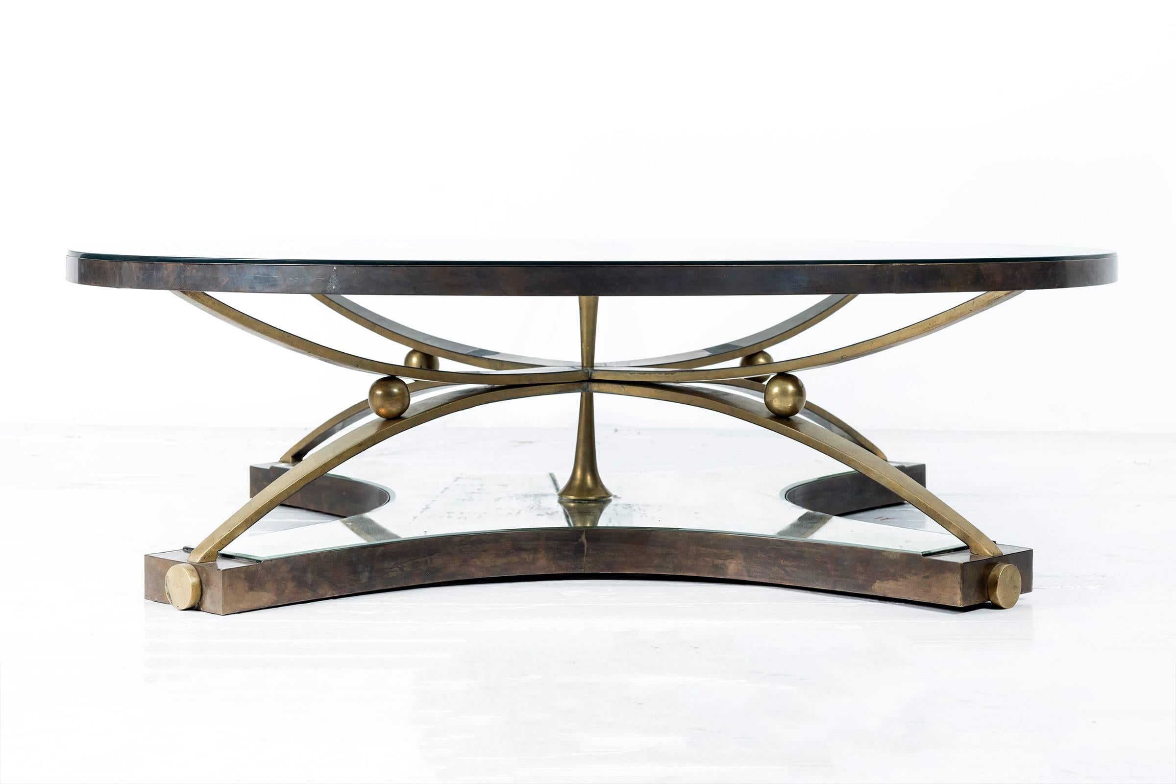 Round glass coffee table raised on sculptural patinated bronze legs,
supported by a mirror-clad bronze cruciform base.
Executed by Talleres Chacon. 
Mexico City, Mexico, c. 1960