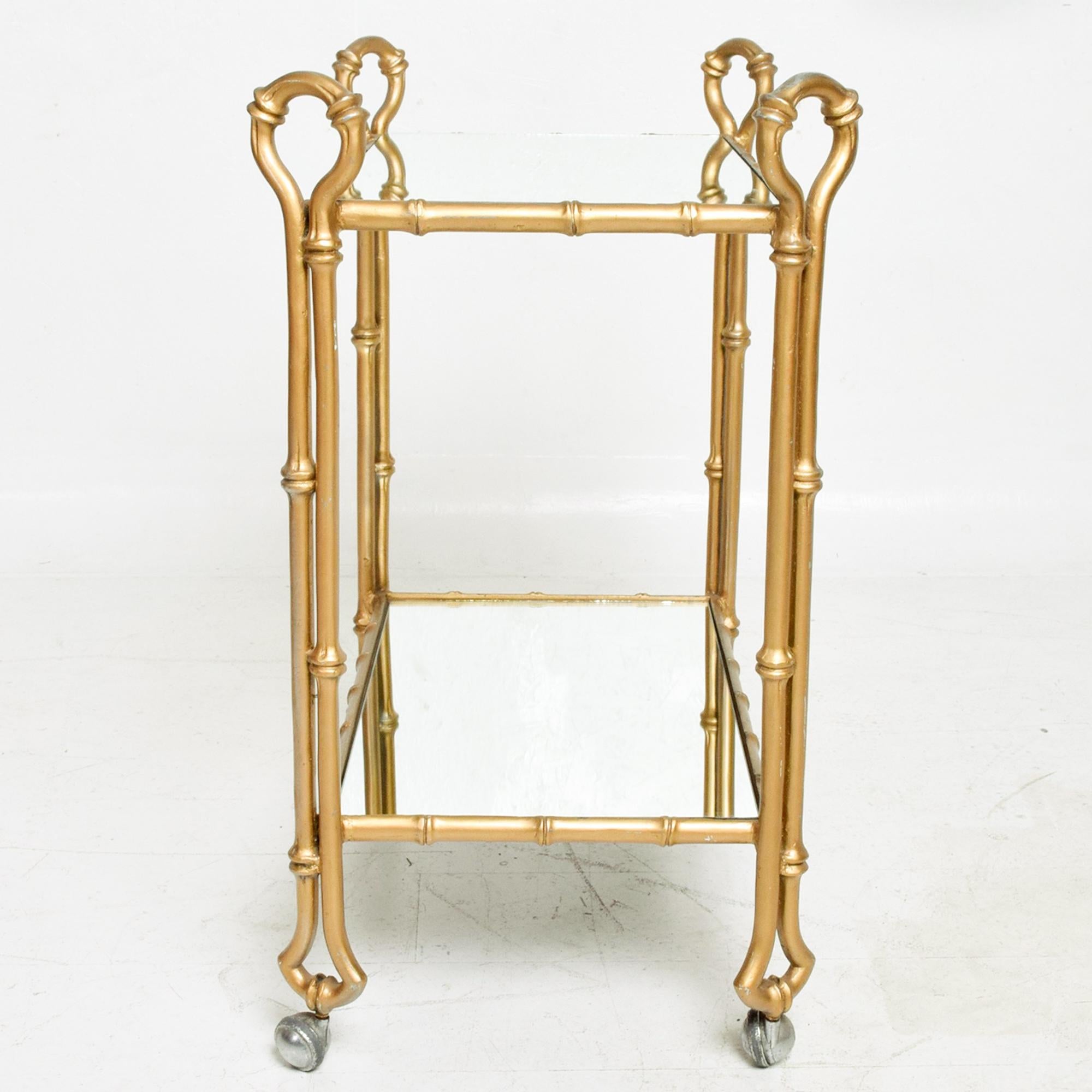 AMBIANIC presents: Mexican Vintage Regency Service Bar Cart in Faux Bamboo 
Gold finish aluminum cart featuring new glass mirror shelves. 
Unmarked. Attributed to Arturo Pani  Mexican Modernism 1950s
Measures: 32.75 tall x 18 W x 27.5 D
Lower tier