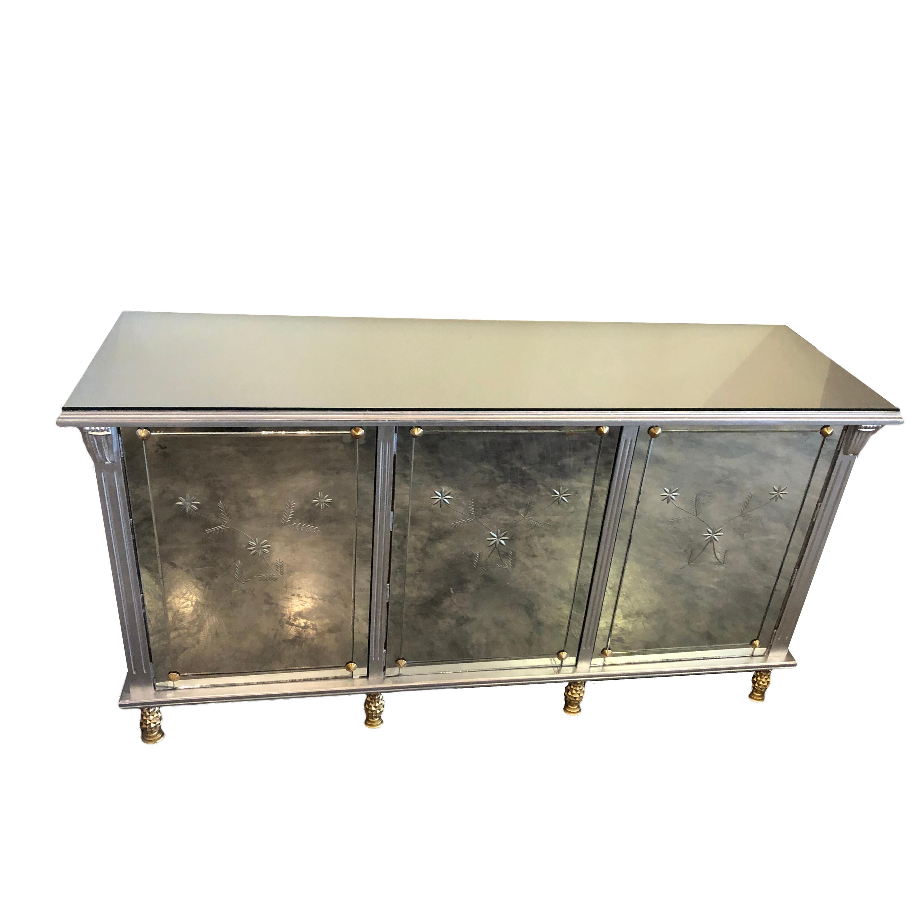 A rare Mexican Mid-Century Modern silver wood credenza by Mexican designer Arturo Pani. The credenza shows a mirror top and 3 doors with mirrors, which show cut floral designs. The central door has 3 drawers. Legs are in the shape of golden pine