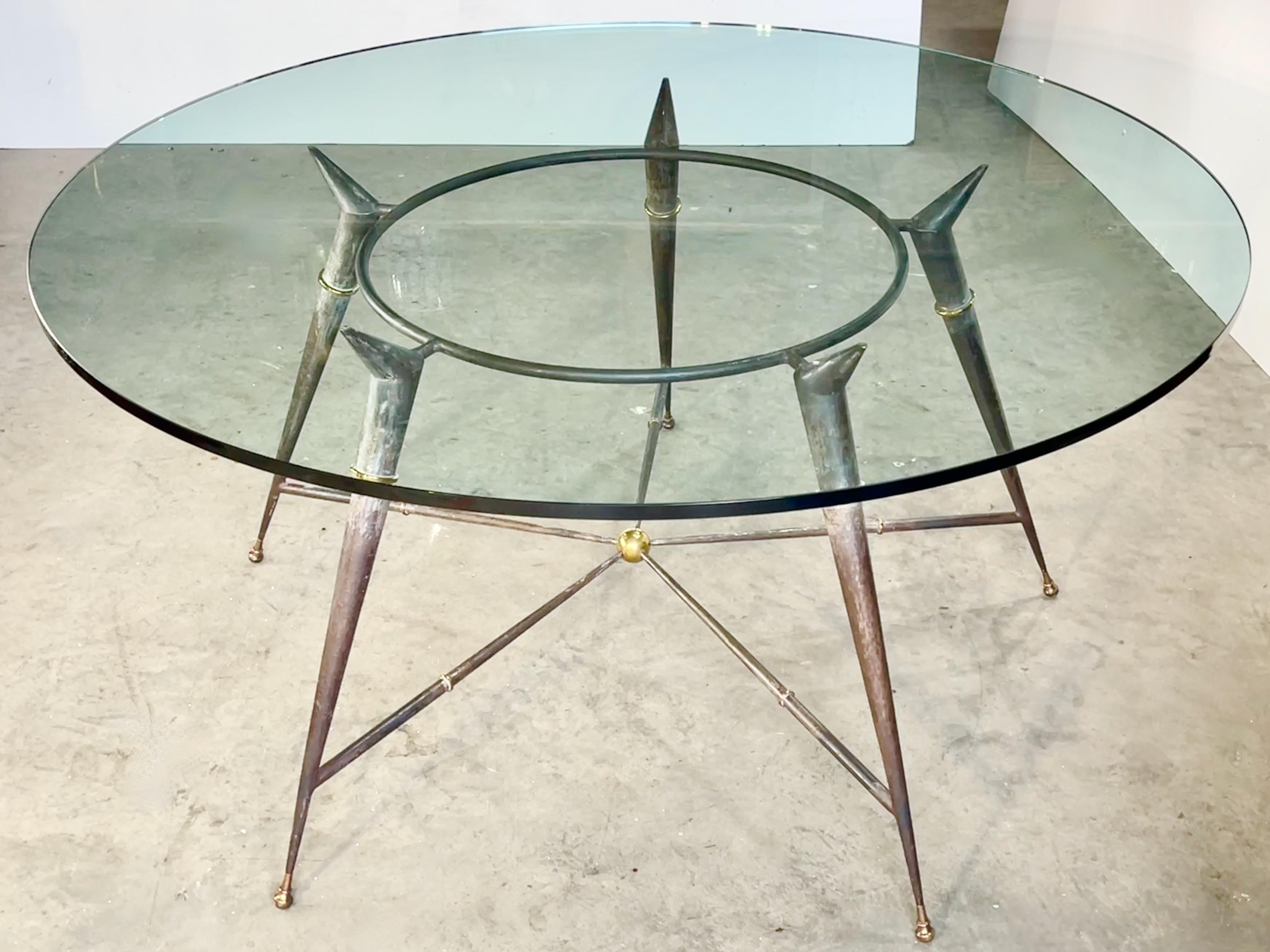 Vintage modernist five tapered leg round garden table made of patinated cast and forged iron with brass sabots and embellishments and a 60 inch round glass top 3/4 inch thick.
Space between legs is 31 inches.
Depth between edge of glass and center