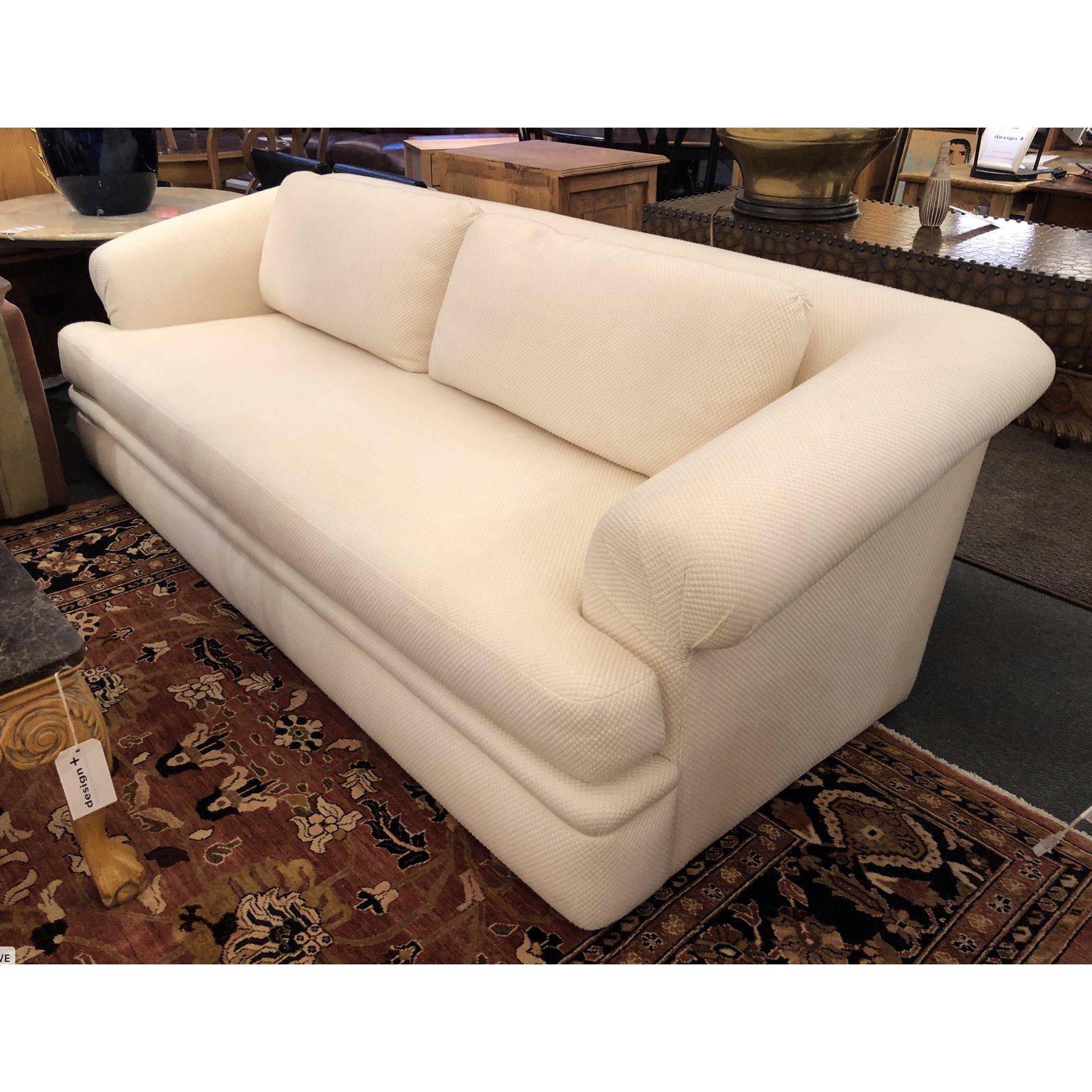 A. Rudin sofa. The sofa has beautifully rolled arms, a bench seat cushion and two back cushions. It is upholstered in an off-white waffle fabric. The sofa has a nice deep seat which makes it extremely comfortable. Seat height: 18 inches.