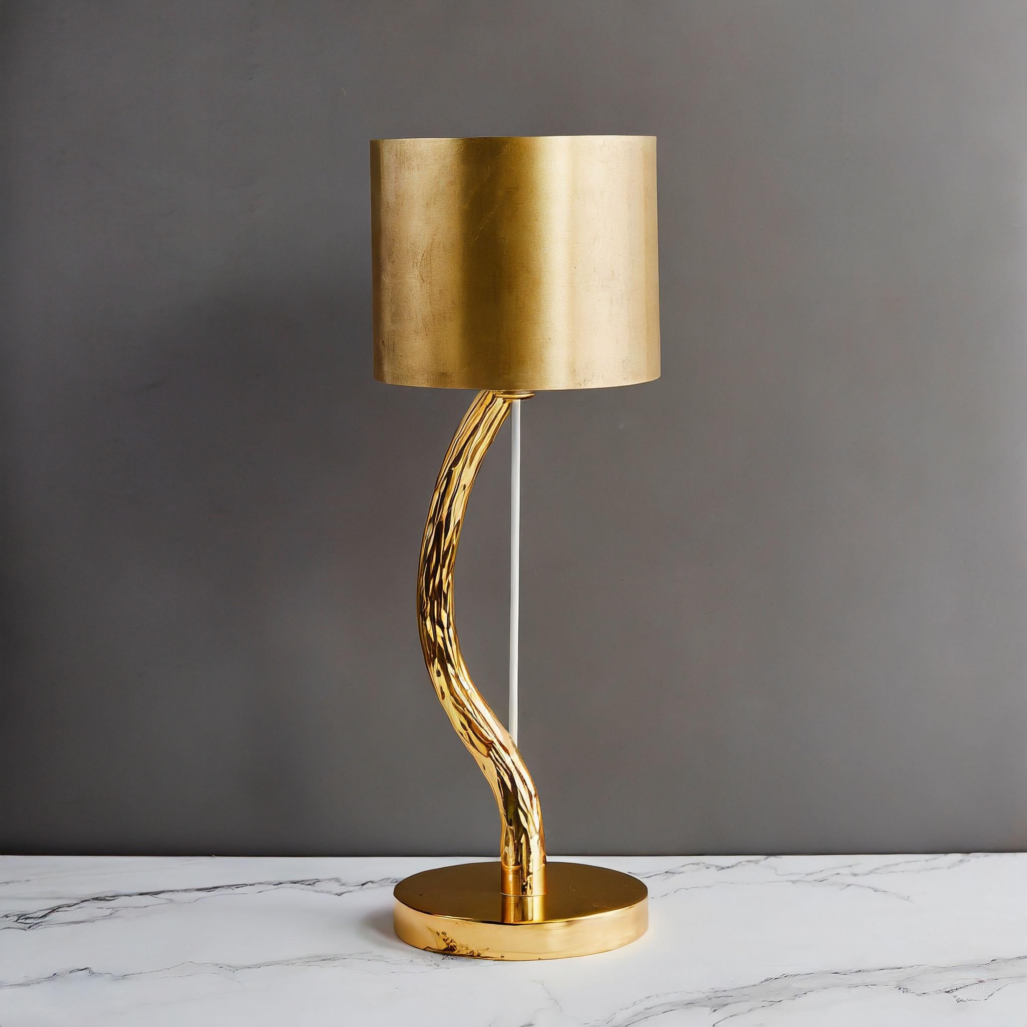 Introducing the 'Arva' golden brass desk lamp: a symphony of elegance and poetry. Crafted with precision, the hammered brass base emulates the graceful form of a tree trunk, adding a touch of natural beauty to any space. Standing proudly at 400mm,