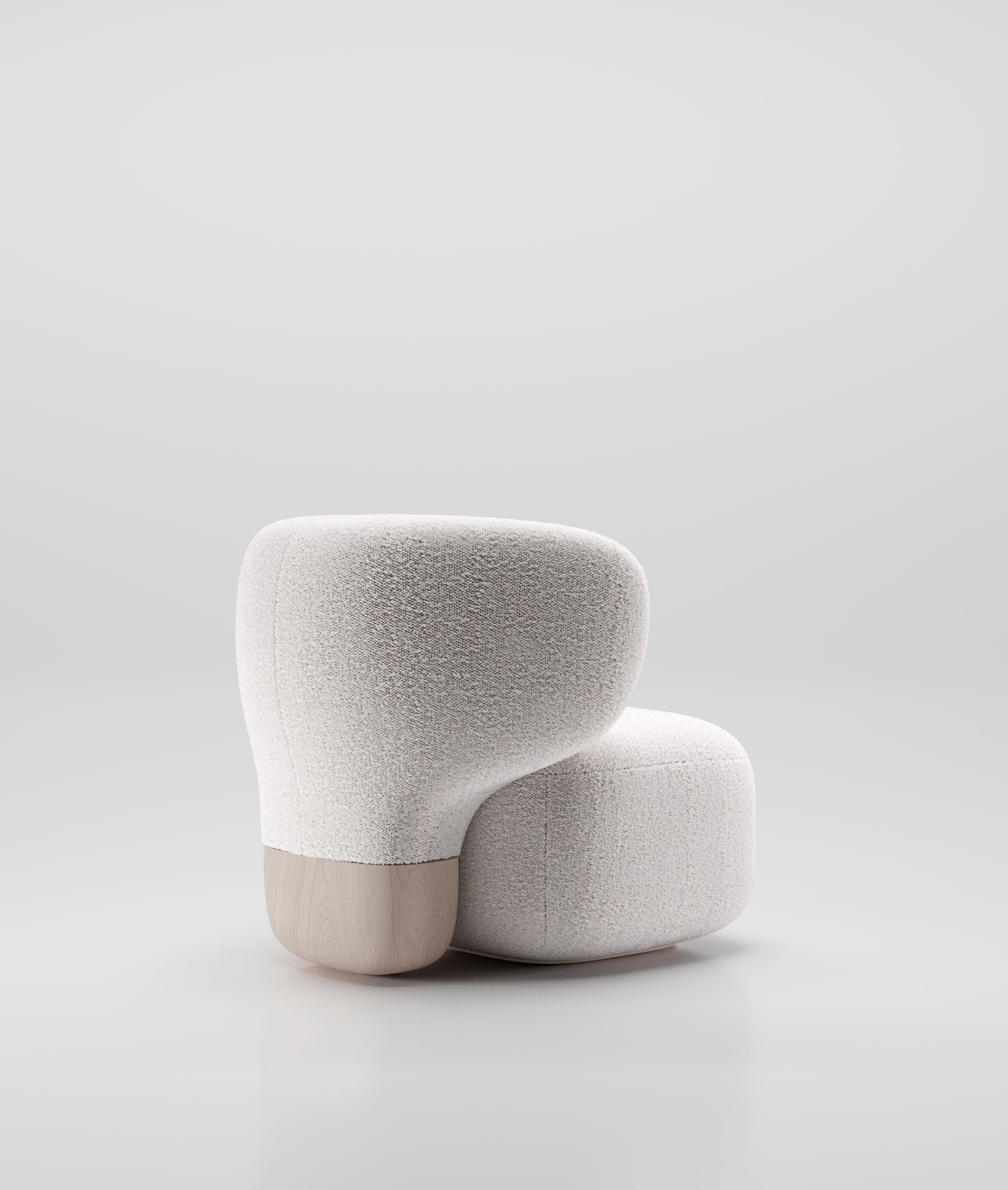 Der Asawa Lounge Chair, der das Asawa Sofa begleitet, zeichnet sich durch eine skulpturale und organische Rückenlehne aus, die aus dem Boden gewachsen zu sein scheint. Ein massives Holzstück dient als Basis für diese geschwungene und umhüllende