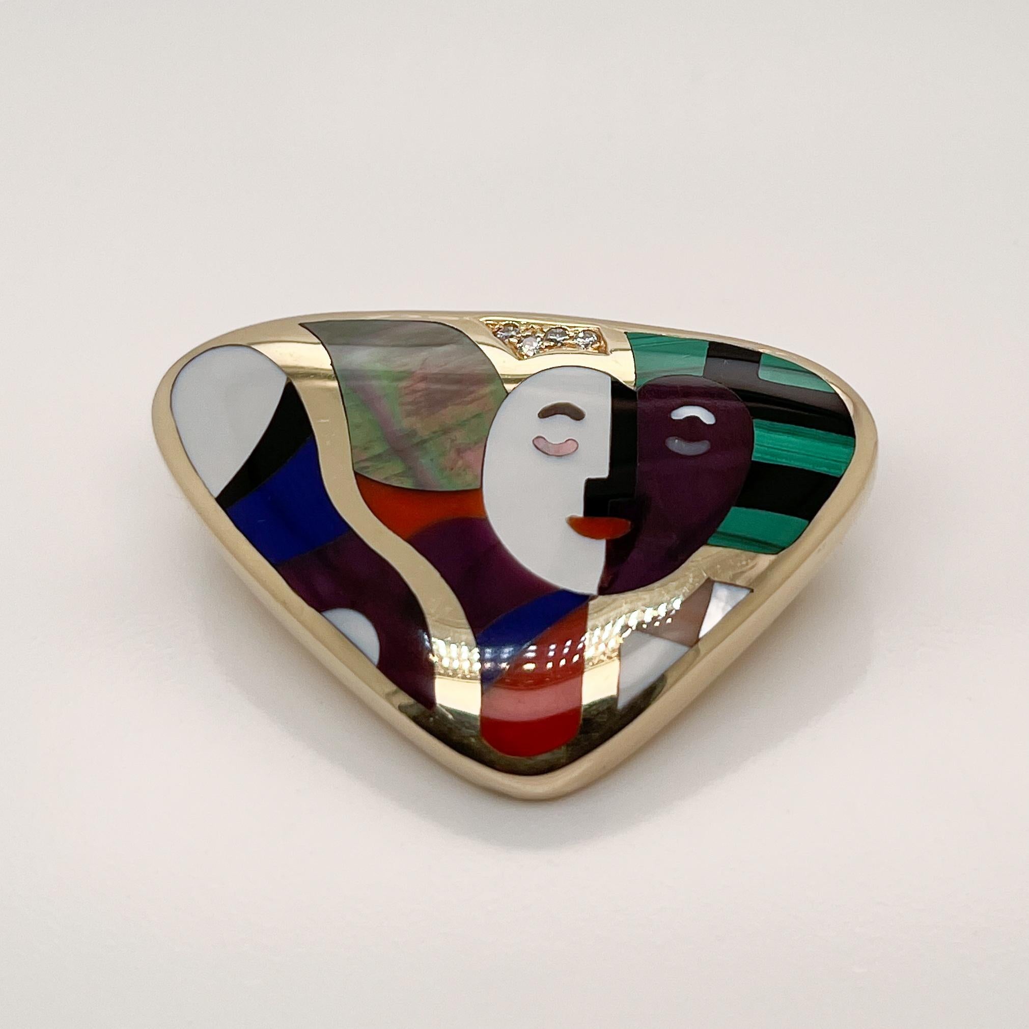 A very fine Asch Grossbardt brooch.

With a stylized portrait of a woman's face with mother of pearl & onyx surrounded by inlaid amethyst, carnelian, lapis, and malachite in 14k gold. 

Pave set with small round brilliant diamonds pave near the