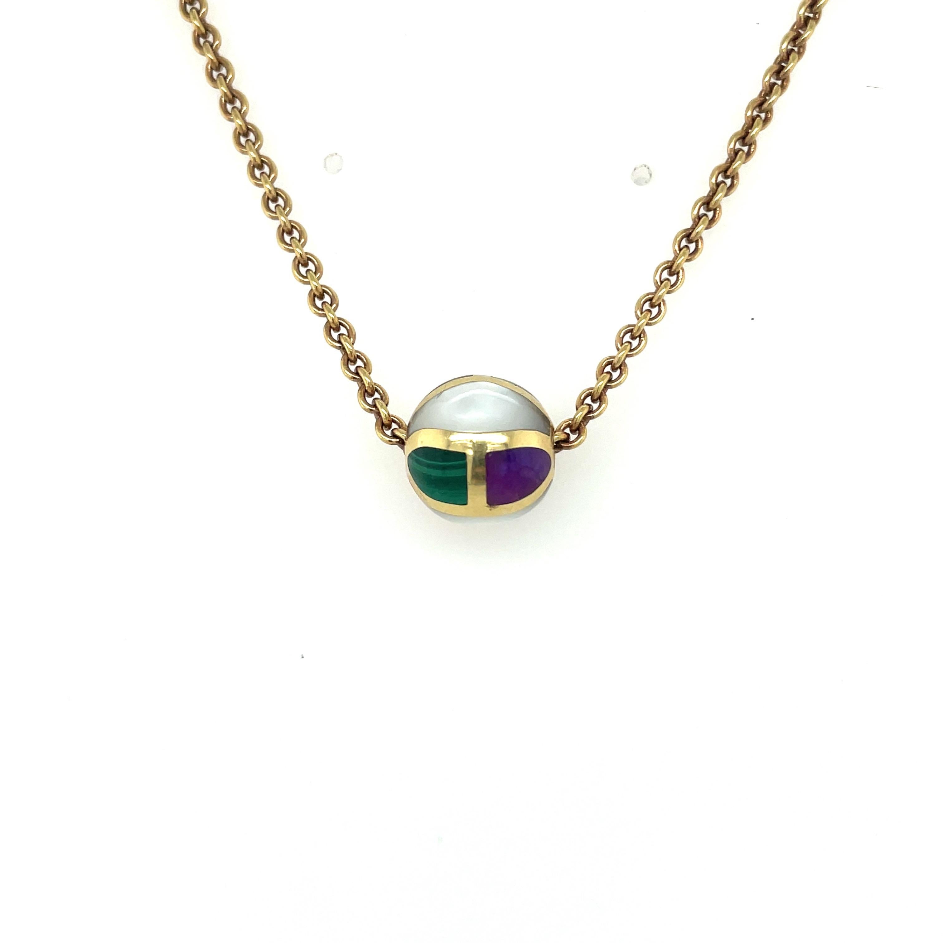 Designed by Asch Grossbardt, this is a very wearable pendant necklace. Designed with a 12 mm yellow gold bead that has been inlaid with mother of pearl, coral, malachite, jasper, onyx and lapis. Each stone section is framed in a shiny yellow gold.
