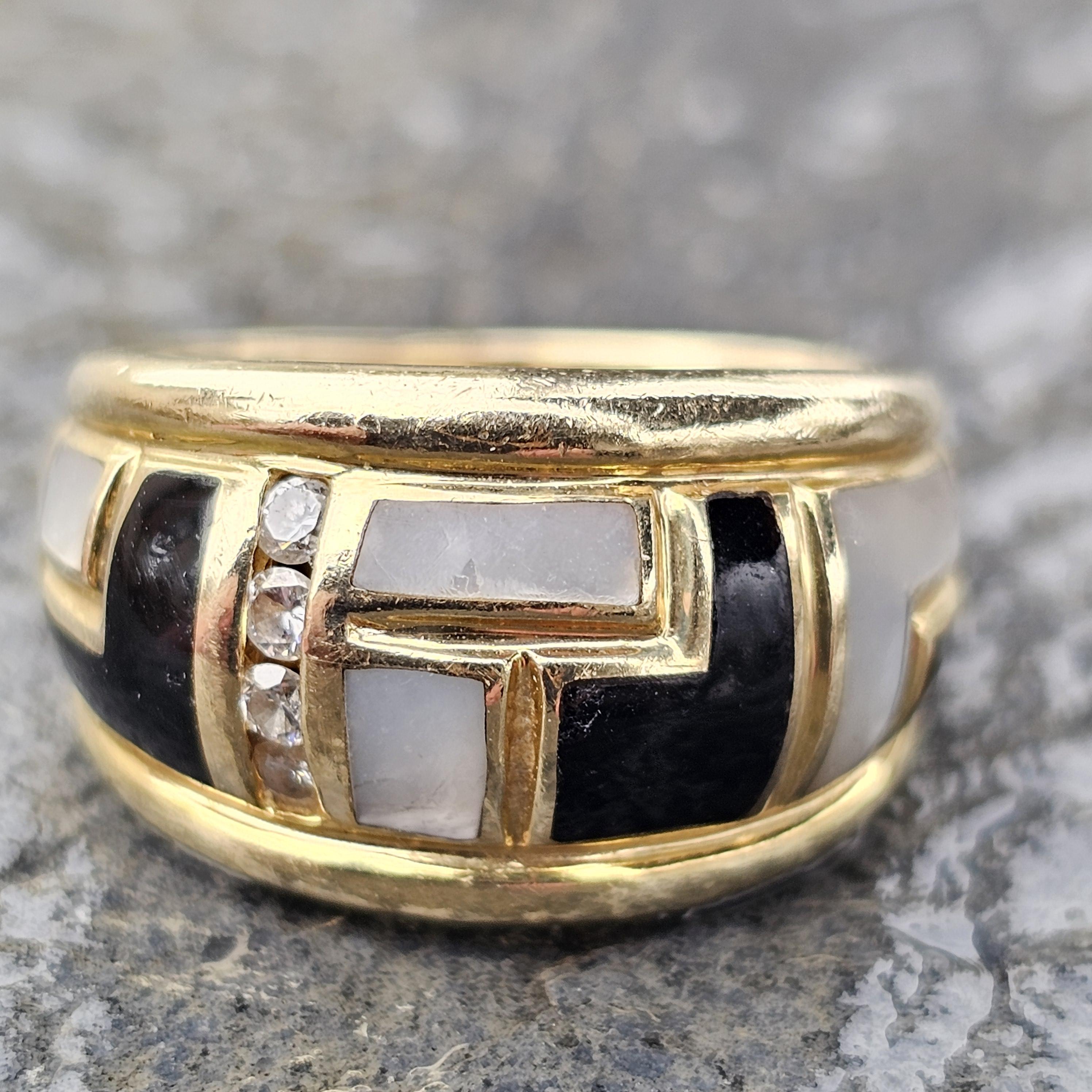 Dieser Bandring ist eine Kreation von Asch Grossbardt. Er wurde mit Präzision gefertigt und besticht durch sein Design mit schwarzen Onyx- und Perlmutt-Intarsien. Das Band ist mit funkelnden Diamanten verziert, die ihm einen Hauch von Brillanz