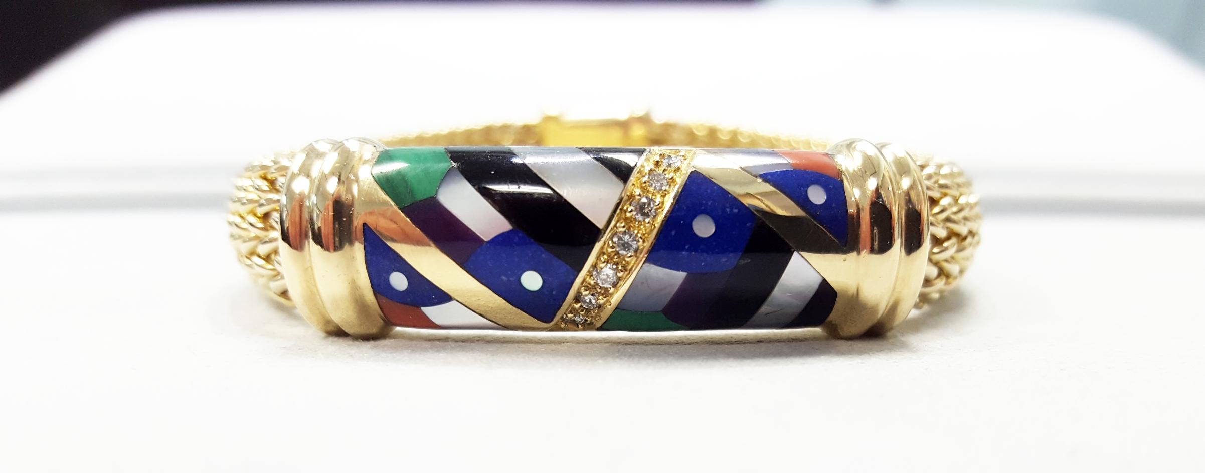 A yellow gold Asch Grossbadt mesh bracelet. The bracelet is inlaid with Black Onyx, Mother of Pearl, Lapis, Malachite, and Coral. The bracelet is also set with 7 Round Brilliant cut diamonds that weigh 0.15cttw. The Bracelet measures 7 inches long