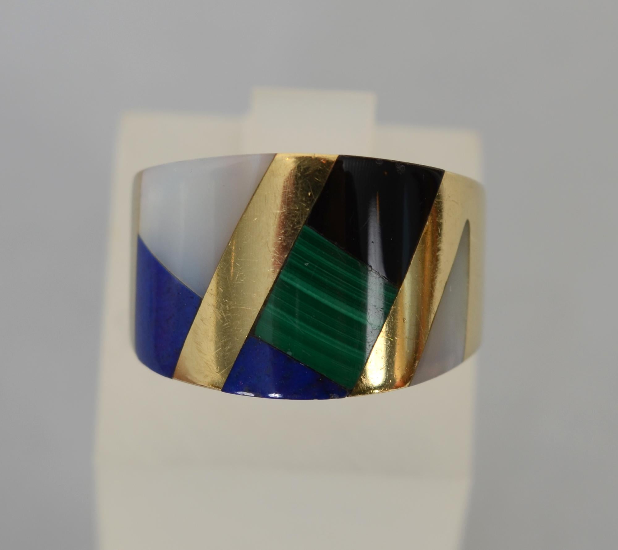Beautiful wide band gold ring with the finely inlaid multistones for which Asch Grossbardt is known. The onyx; malachite; lapis lazuli and mother of pearl are separated by diagonal bands of 14 karat gold. The ring is 9/16