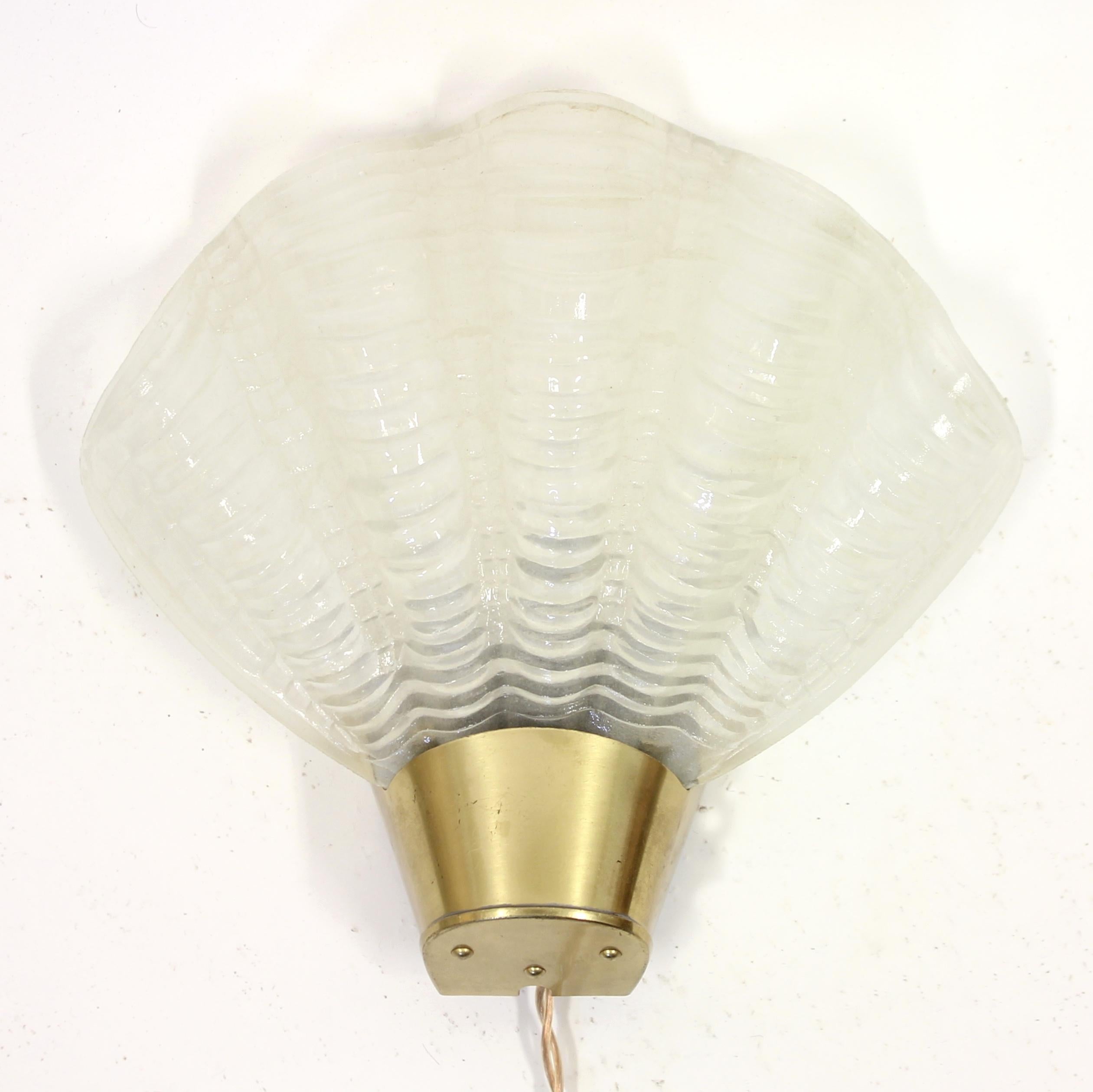 Mid-century shell shaped wall scone / wall lamp made by Swedish manufacturer ASEA in the 1950s. Bottom part made of brass, mounted with a glass shade in form of a shell. Overall good vintage condition with light ware consistent with age and use.