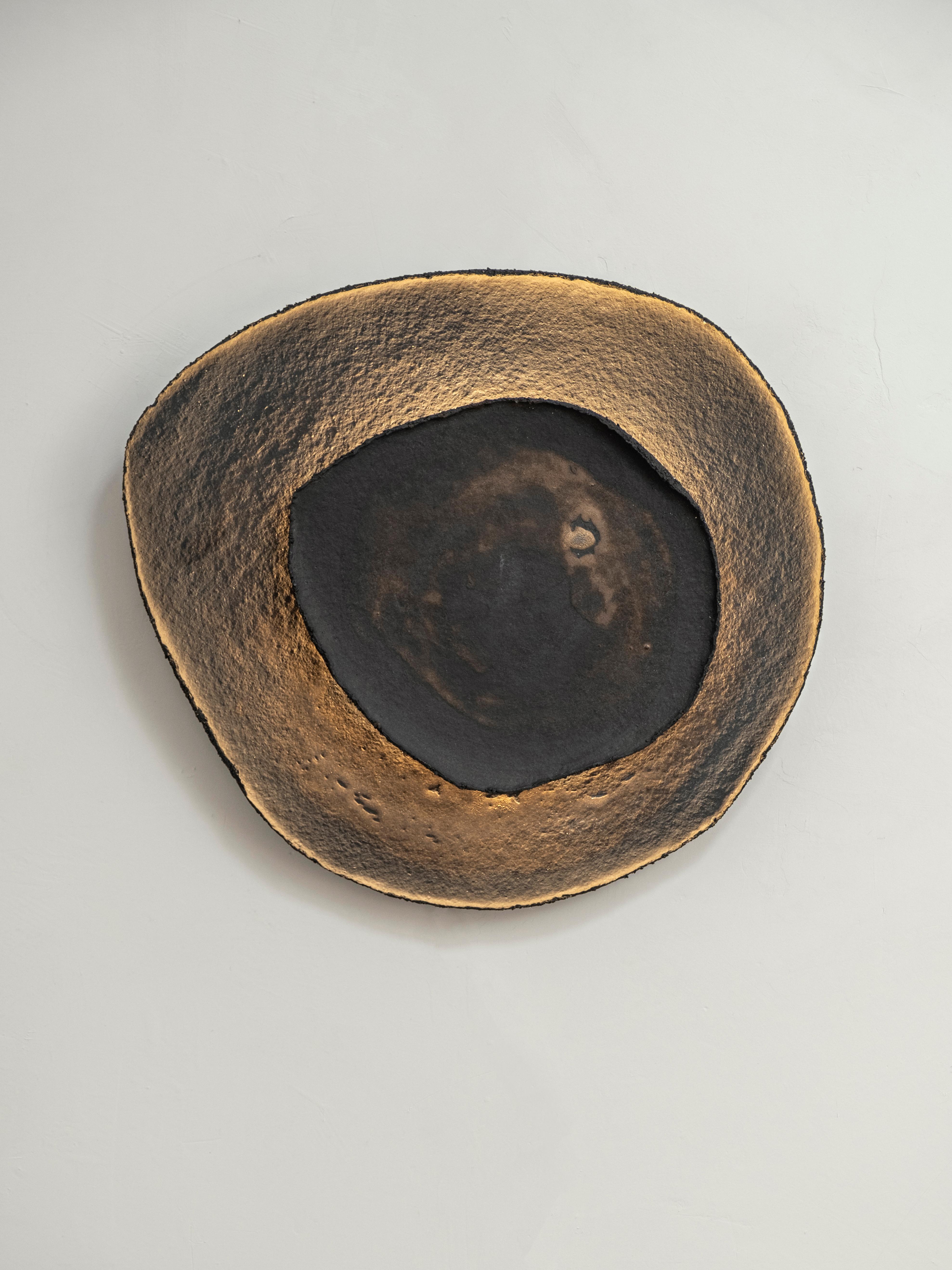 Ash #11 wall light by Margaux Leycuras
One of a Kind, Signed and numbered
Dimensions: Ø44 x H48 cm.
Material: Ceramic, black stoneware with burnished gold glaze.
The piece is signed, numbered and delivered with a certificate of