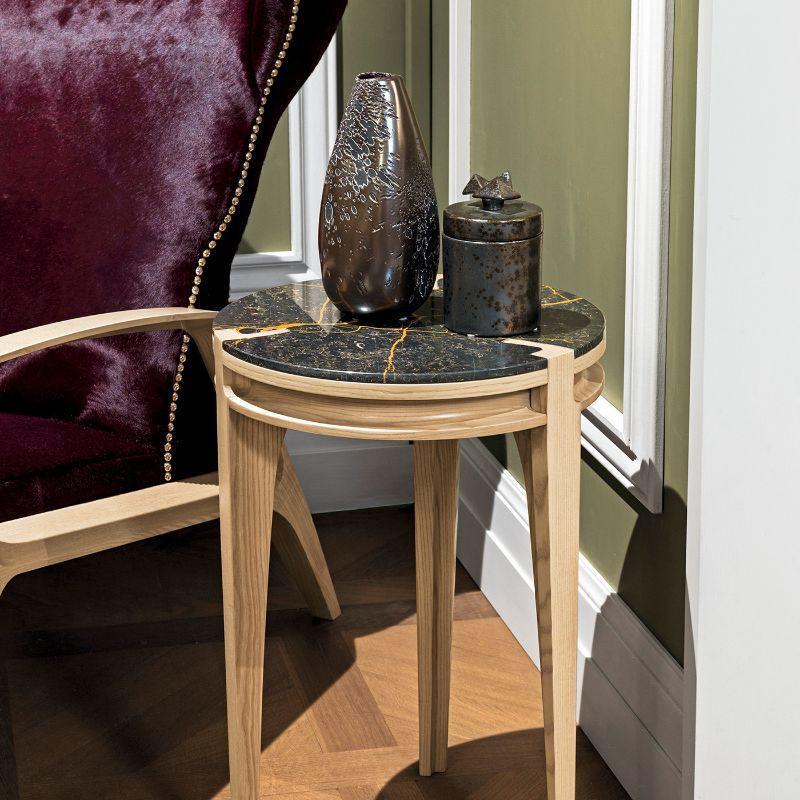 A stupendous furniture piece that combines aesthetic and functionality in a clean and timelessly elegant design, this side table features a precious ash wood base supporting a round, striking top in Noir Saint Laurent marble. Available in other